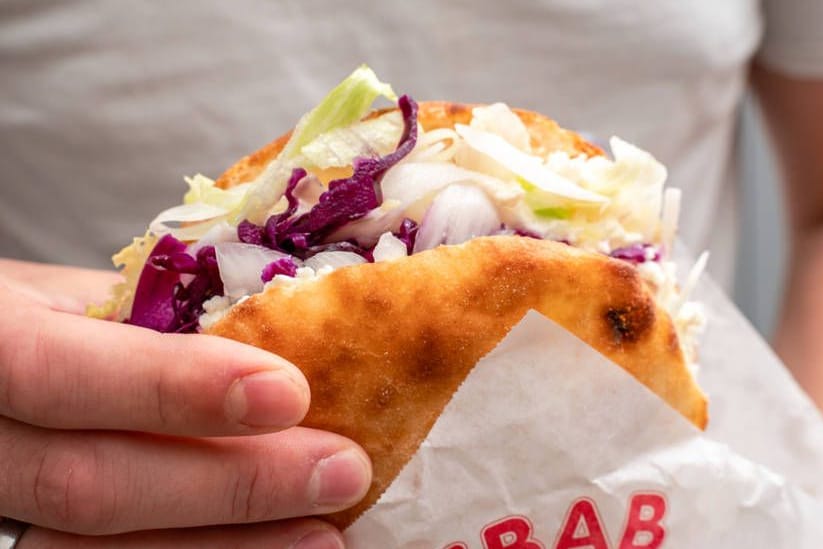 Mann hält einen Döner (Symbolfoto): In der Dresdner Neustadt gibt es am Donnerstag ein besonderes Angebot.