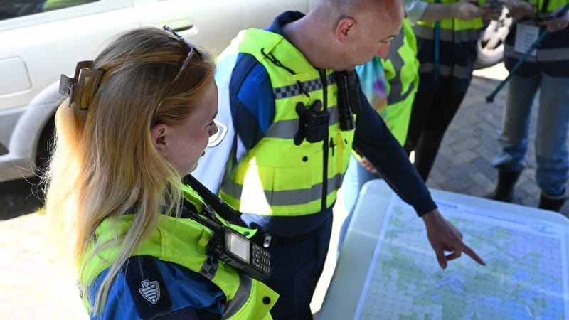 Einsatzkräfte blicken auf eine Karte mit dem Suchgebiet.