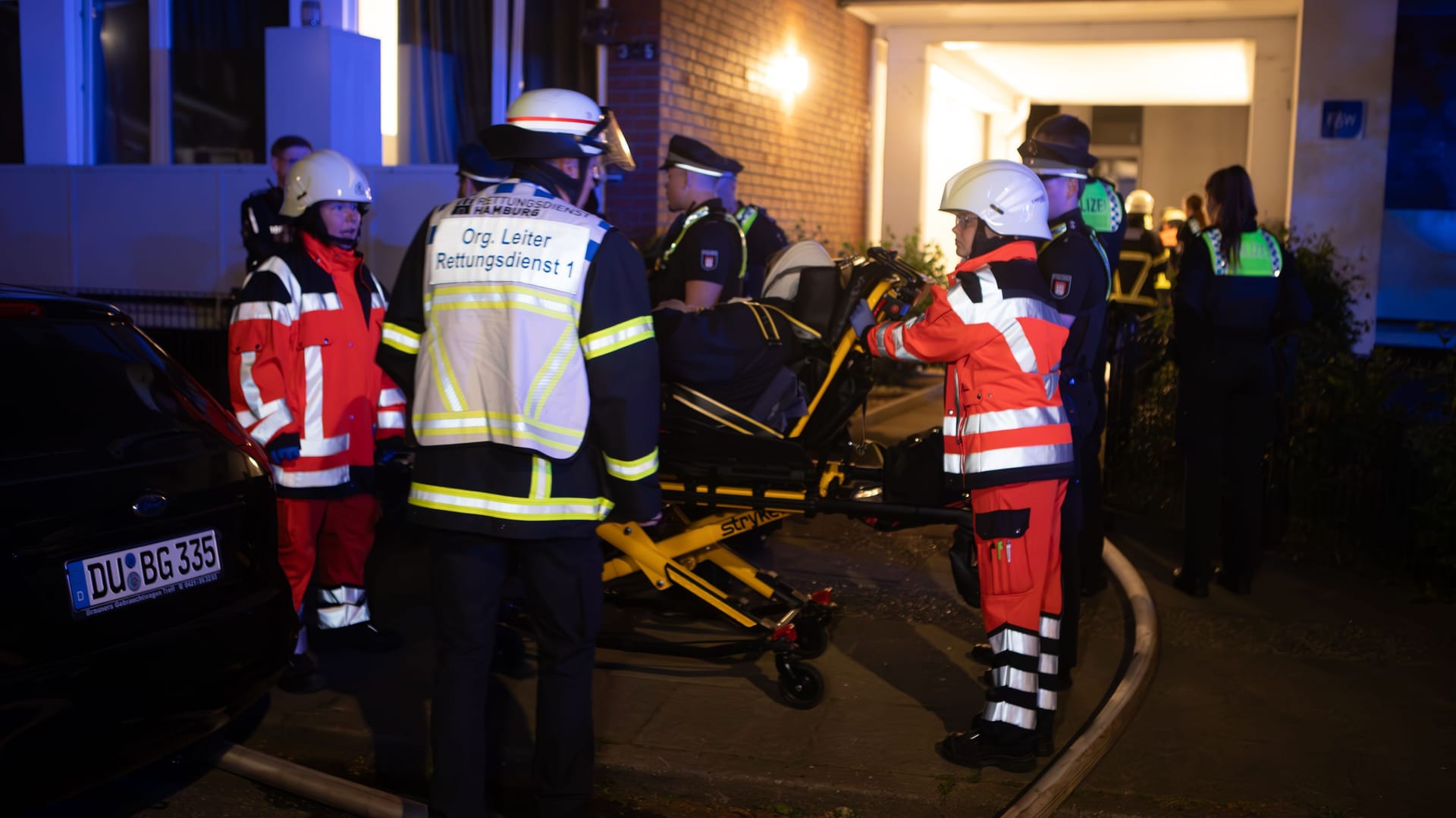 Rettungskräfte versorgen eine verletzte Person: In Hamburg hat es in der Nacht in einer Wohnunterkunft gebrannt.