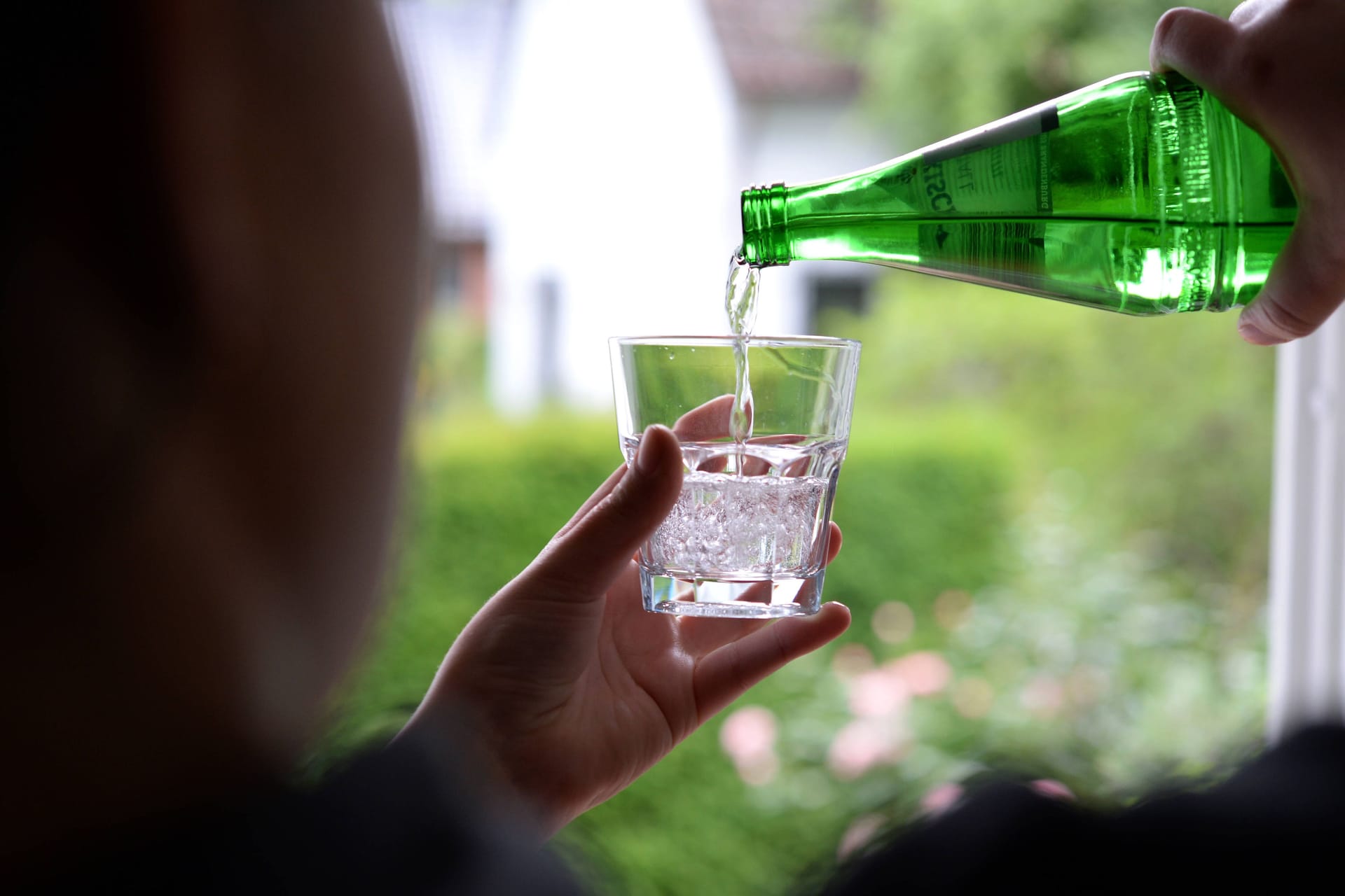 Eine Frau gießt sich Mineralwasser in eine Flasche (Symbolfoto): In Frankreich wurden einer Mutter die Drogen ihres Sohnes zum Verhängnis.