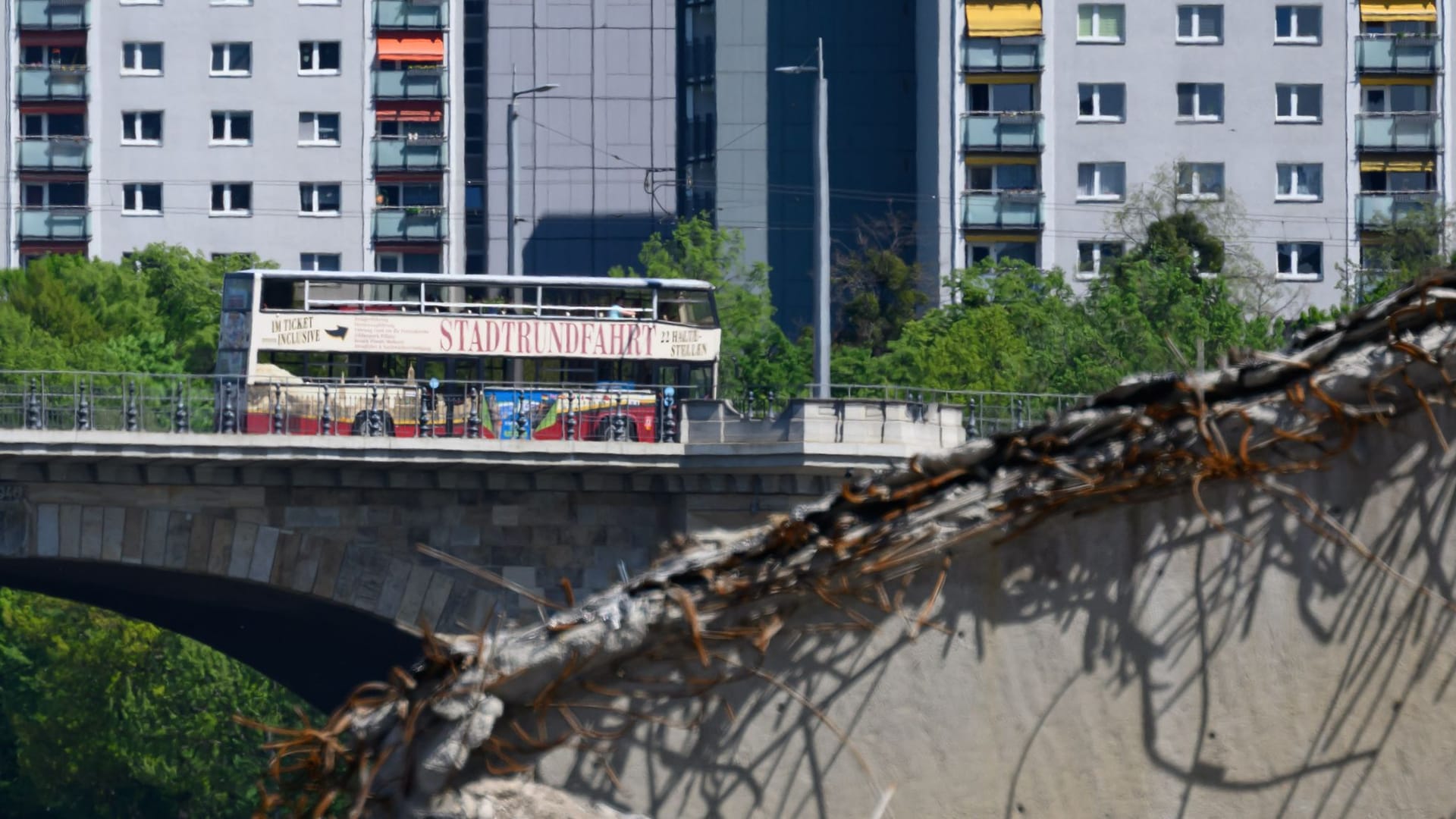 Blick auf den teileingestürzten Brückenzug der Carolabrücke während im Hintergrund ein Bus der Stadtrundfahrt über die Albertbrücke fährt. Ein Teil der 1971 in Betrieb genommenen Brücke mit Straßenbahngleisen und Radweg war in der Nacht zum 11. September 2024 völlig überraschend eingestürzt.