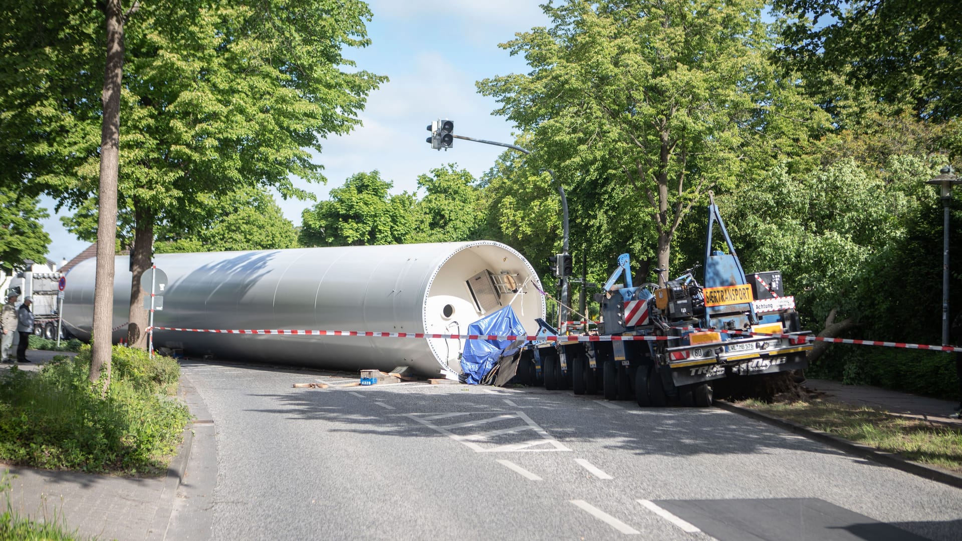 In der Nacht zum Freitag (16.05.2025) ist in Elmshorn (Landkreis Pinneberg) ein Schwertransporter am Rande der Innenstadt verunglückt. Der Lkw hatte ein tonnenschweres Bauteil einer Windkraftanlage geladen, das bei dem Unfall vom Auflieger stürzte und seitdem den Heidmühlenweg blockiert. Nach Angaben der Polizei kam das Fahrzeug gegen 2 Uhr aus bislang ungeklärter Ursache von der Fahrbahn ab. Zwei weitere Transporter, die zum selben Konvoi gehören, stehen derzeit hinter der Unfallstelle fest, ein Wenden oder Zurücksetzen ist aufgrund ihrer Größe nicht möglich.Die Bergung des Windrad-Teils gestaltet sich aufwendig und kann voraussichtlich erst in der kommenden Woche erfolgen. Spezielle Technik und Fahrzeuge sind dafür notwendig. Der betroffene Bereich bleibt bis dahin gesperrt, der Verkehr wird weiträumig umgeleitet. Foto: NEWS5 / Sebastian Peters Weitere Informationen... https://www.news5.de/news/news/read/36603