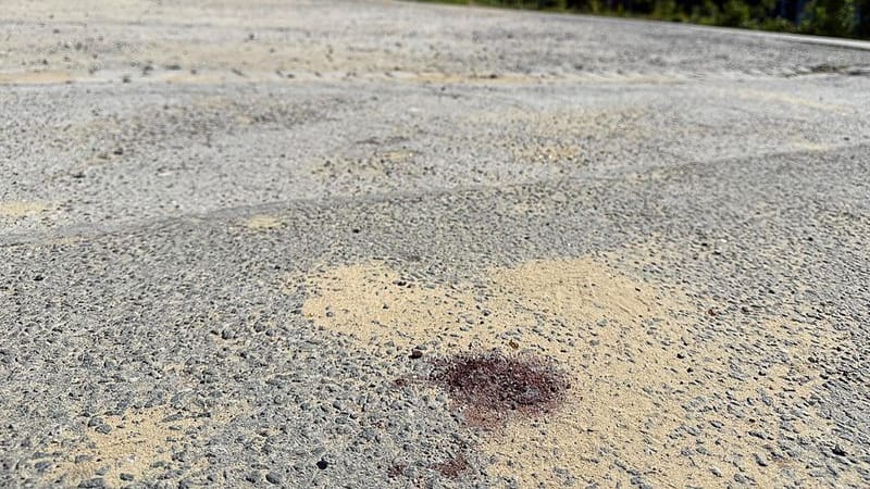 Ein Blutfleck ist auf dem Asphalt am Tatort in Menden im Sauerland zu sehen. Nach dem gewaltsamen Tod eines 14-Jährigen ermittelt die Polizei.