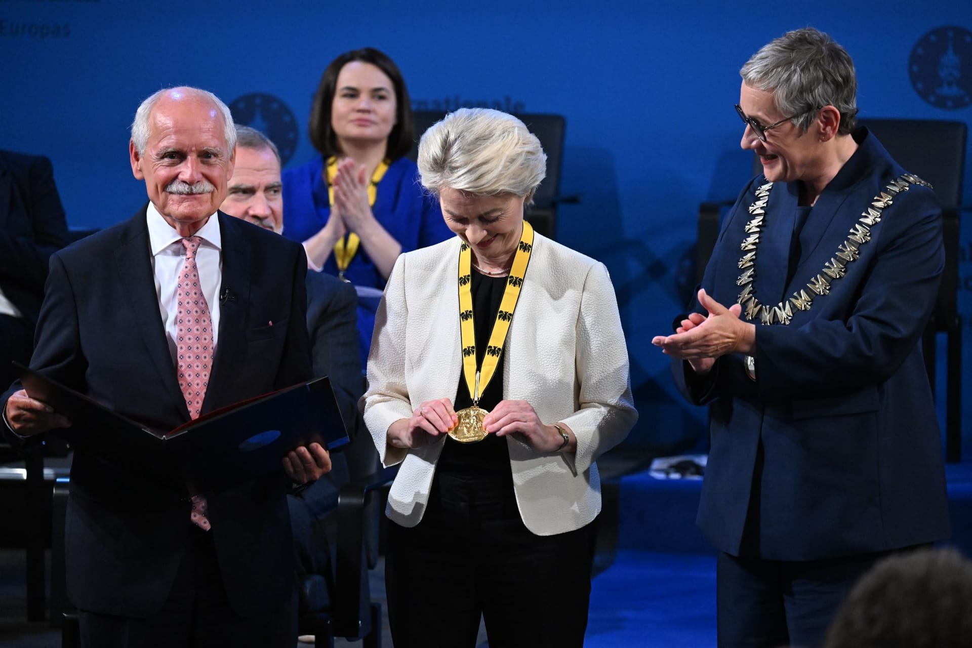 Aachen: Ursula von der Leyen (M), Präsidentin der Europäischen Kommission, betrachtet bei der Verleihung des Internationalen Karlspreises im Rathaus neben Jürgen Linden (l), Vorsitzender des Karlspreis-Direktoriums, und Sibylle Keupen (r), Oberbürgermeisterin von Aachen, die Medaille.