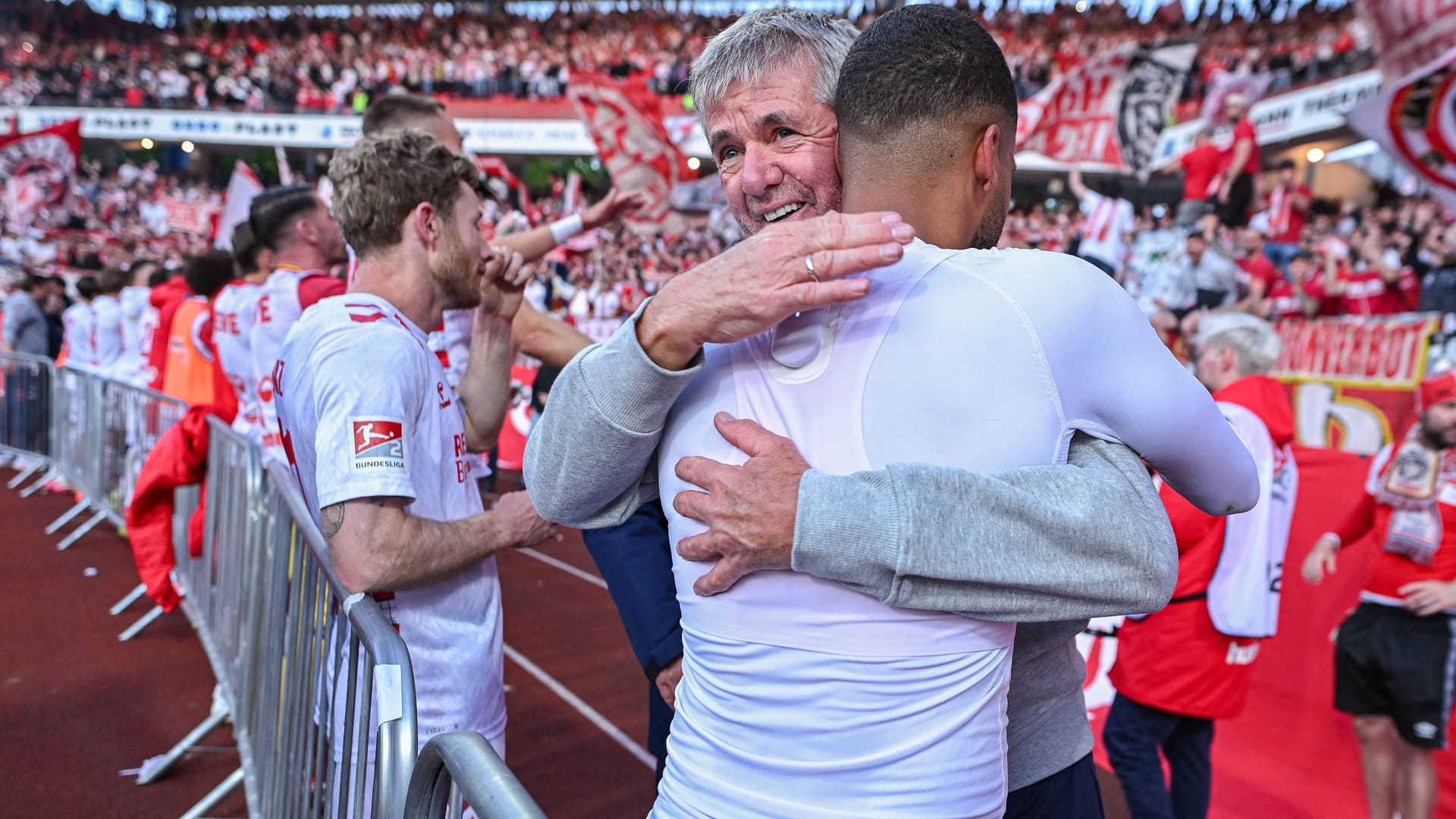 Der neue Trainer Friedhelm Funkel umarmt Linton Maina nach dem Auswärtssieg.