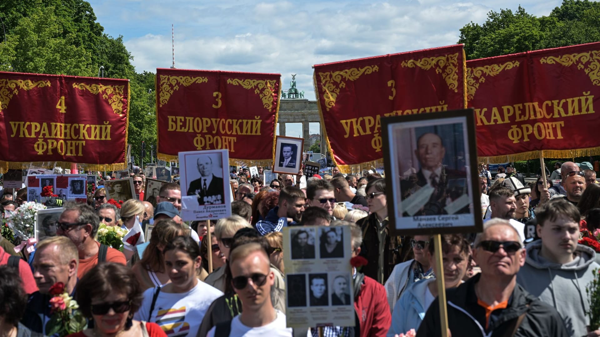 Menschen halten historische Truppenbanner in der Nähe des Sowjetischen Ehrenmal im Tiergarten, das an die während des Zweiten Weltkriegs gefallenen sowjetischen Soldaten erinnert.