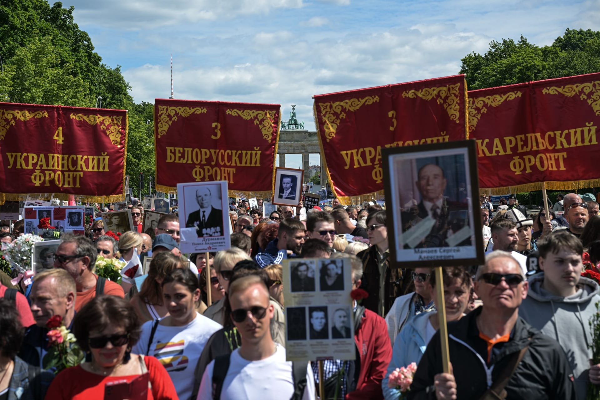 Menschen halten historische Truppenbanner in der Nähe des Sowjetischen Ehrenmal im Tiergarten, das an die während des Zweiten Weltkriegs gefallenen sowjetischen Soldaten erinnert.