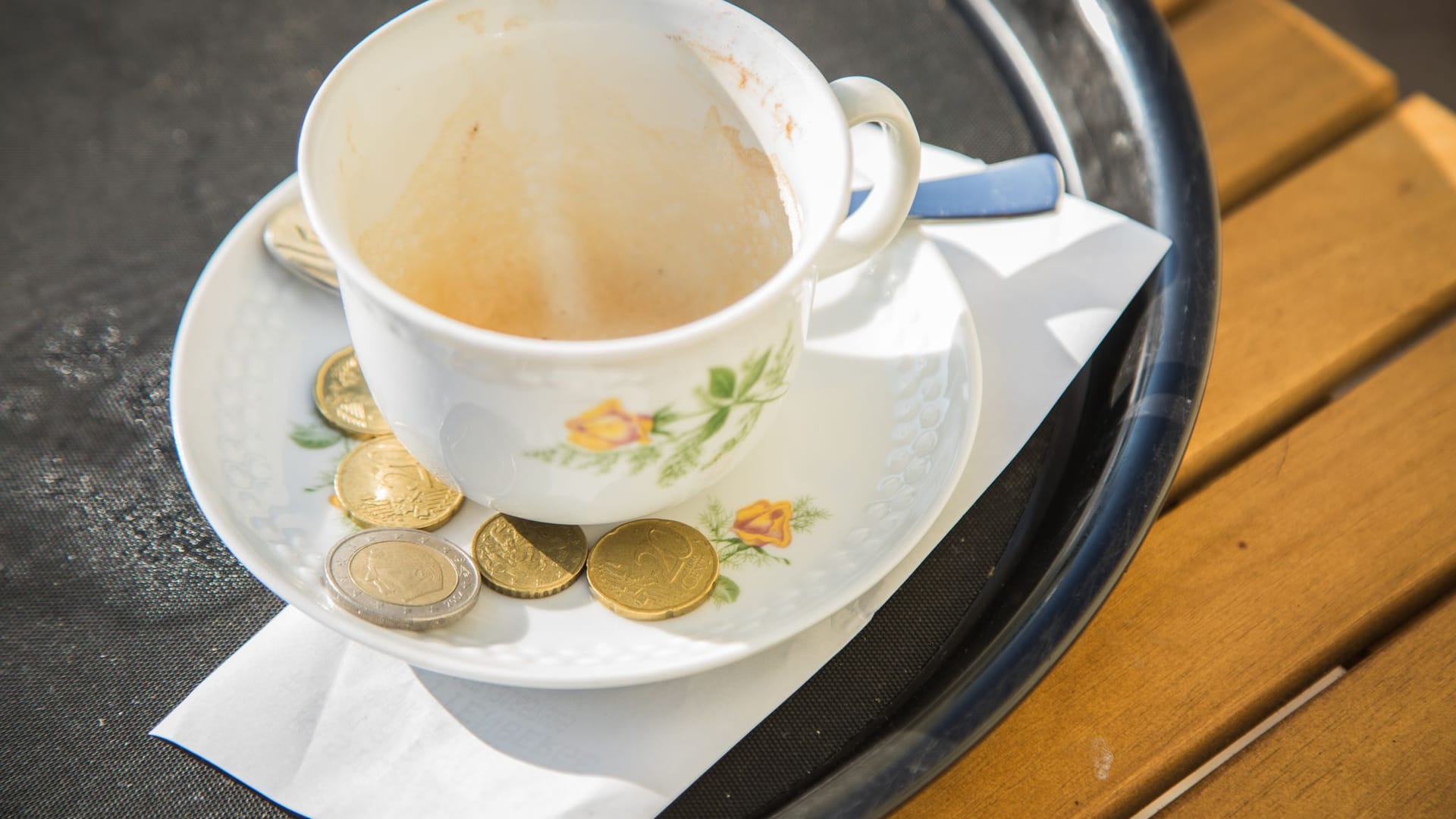 Trinkgeld liegt neben einem Cappuccino auf einem Tablett Trinkgeld liegt neben einem Cappuccino auf einem Tablett