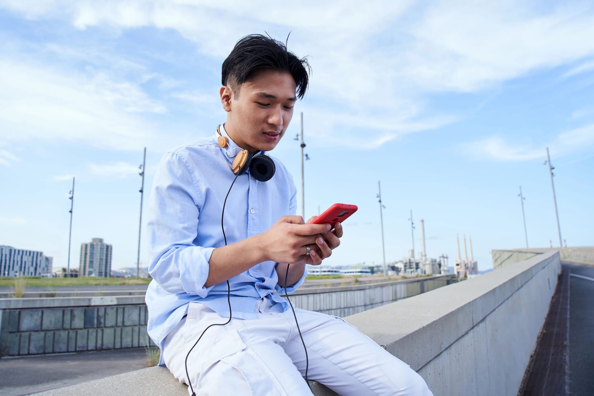 Concentrated Asian young man using cell phone outdoors. People communicating chatting online apps.