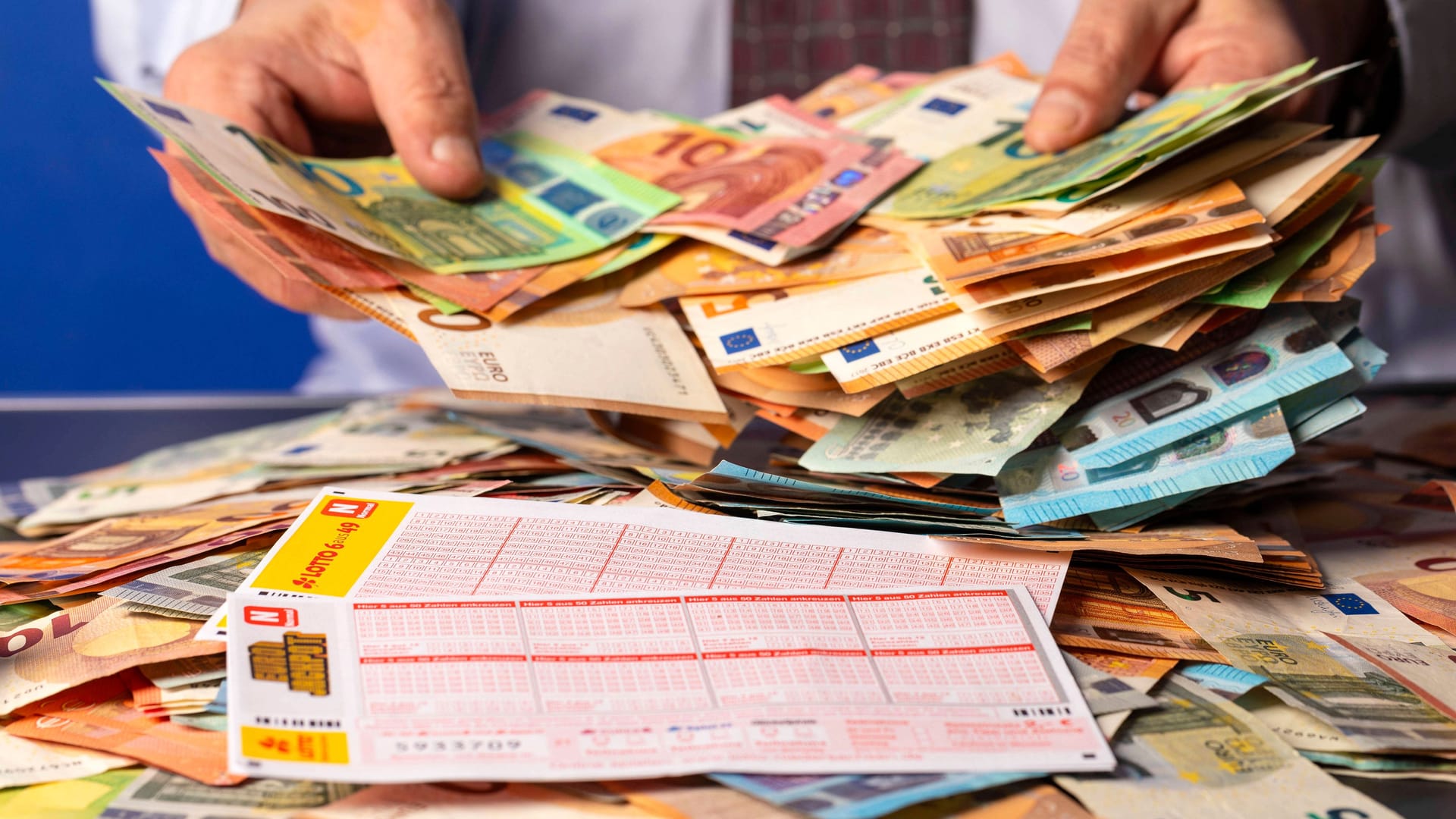 Lottogewinner mit Lottoschein, Eurojackpot-Schein und Bargeld (Symbolfoto): Ein Spieler aus Nordrhein-Westfalen hat am Dienstagabend eine große Summe im Eurojackpot gewonnen.