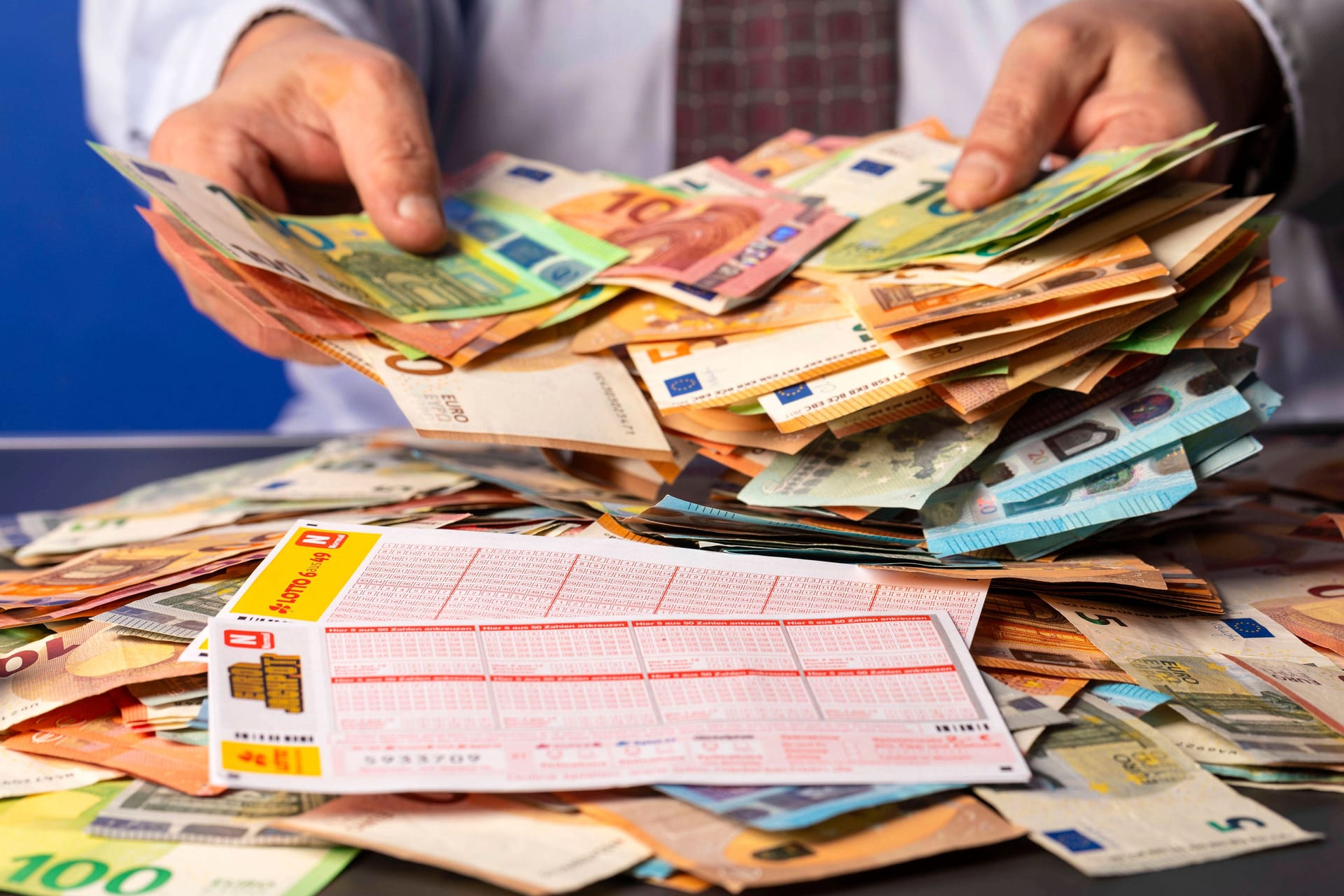 Lottogewinner mit Lottoschein, Eurojackpot-Schein und Bargeld (Symbolfoto): Ein Spieler aus Nordrhein-Westfalen hat am Dienstagabend eine große Summe im Eurojackpot gewonnen.