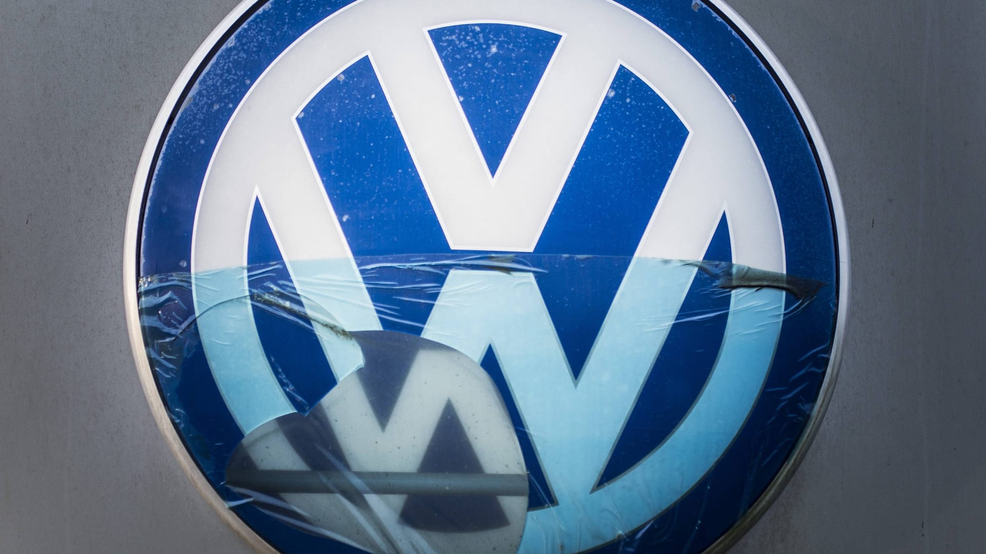 Ein beschädigtes VW-Logo (Symbolbild): Der Dieselskandal hat Volkswagen Milliarden gekostet – und bringt Manager nun in Erklärungsnot.