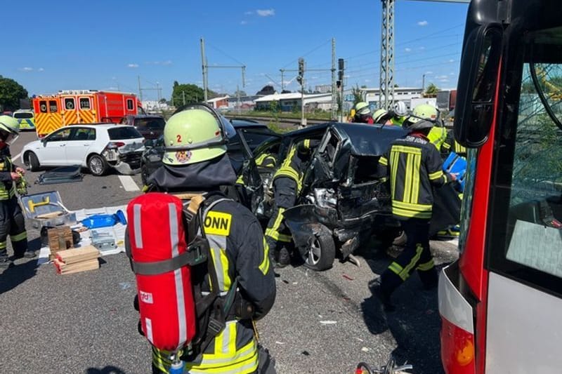 Unfallstelle: Feuerwehrleute stehen vor Pkw, die bei einem Unfall ineinander geschoben wurden.