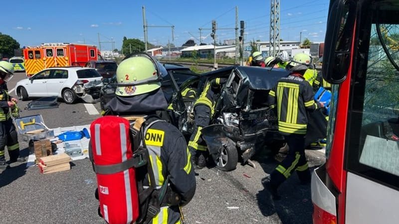 Unfallstelle: Feuerwehrleute stehen vor Pkw, die bei einem Unfall ineinander geschoben wurden.
