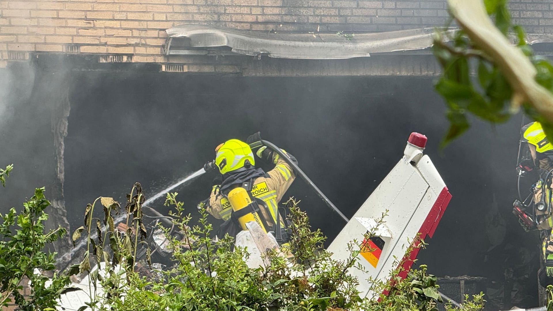 Die Feuerwehr arbeitet an der Absturzstelle, nachdem ein Flugzeug in ein Wohnhaus gestürzt ist.