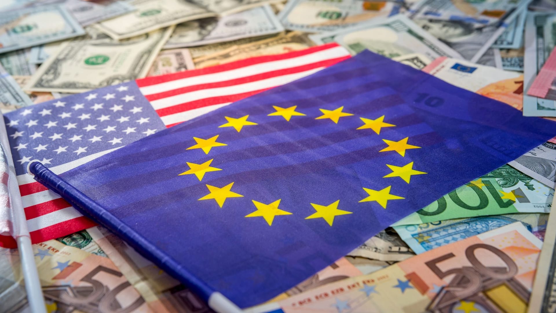Europäische und US-Flagge auf einem Untergrund mit Geldscheinen
