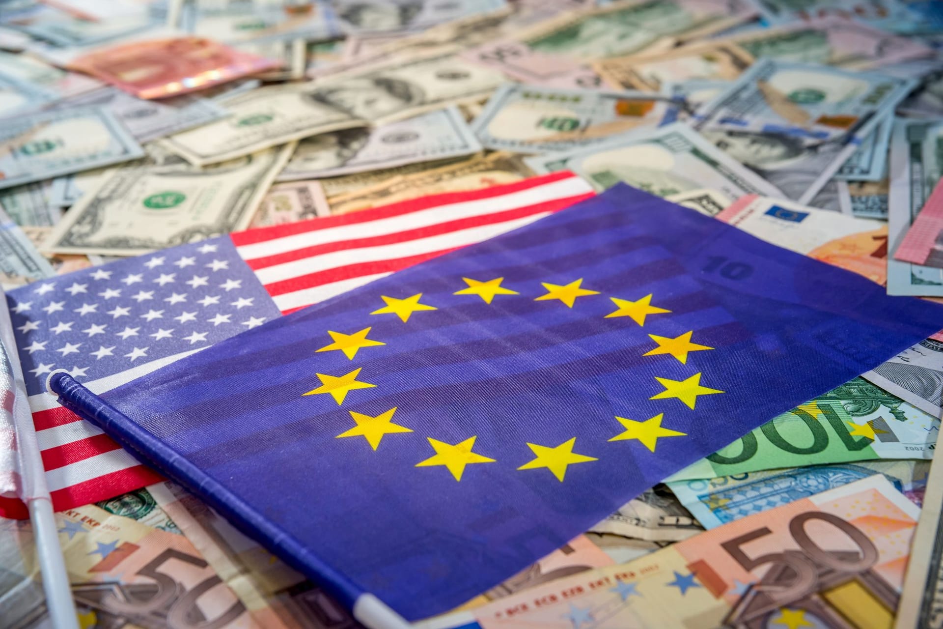 Europäische und US-Flagge auf einem Untergrund mit Geldscheinen