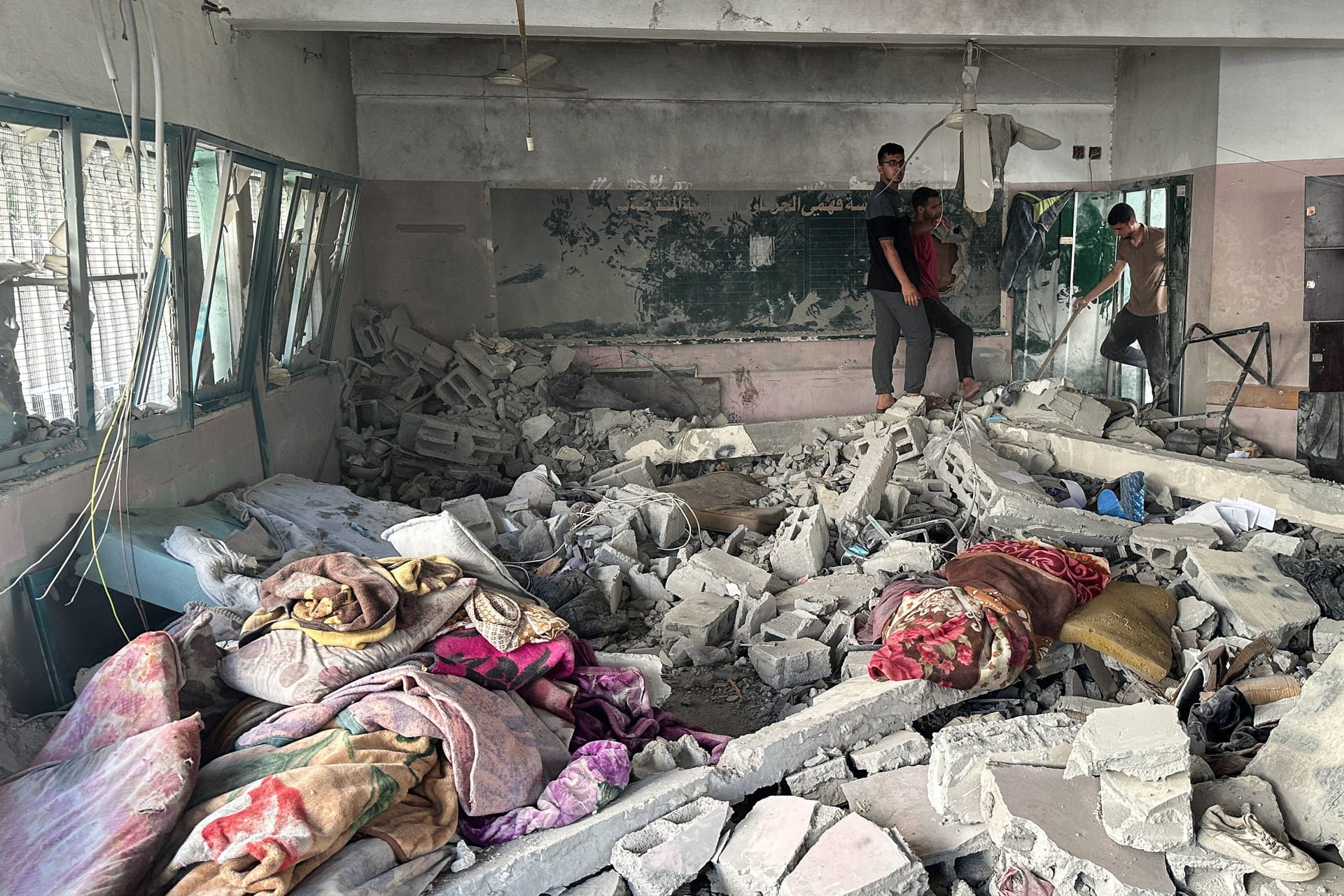 Drei Männer in der nach dem israelischen Angriff beschädigten Schule.
