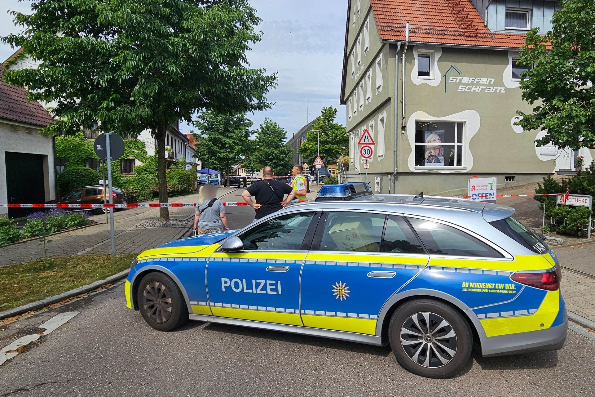Eine Straße ist mit einem Polizeifahrzeug und Polizeiflatterband abgesperrt. In Wangen im Kreis Göppingen ist ein Mann erschossen worden