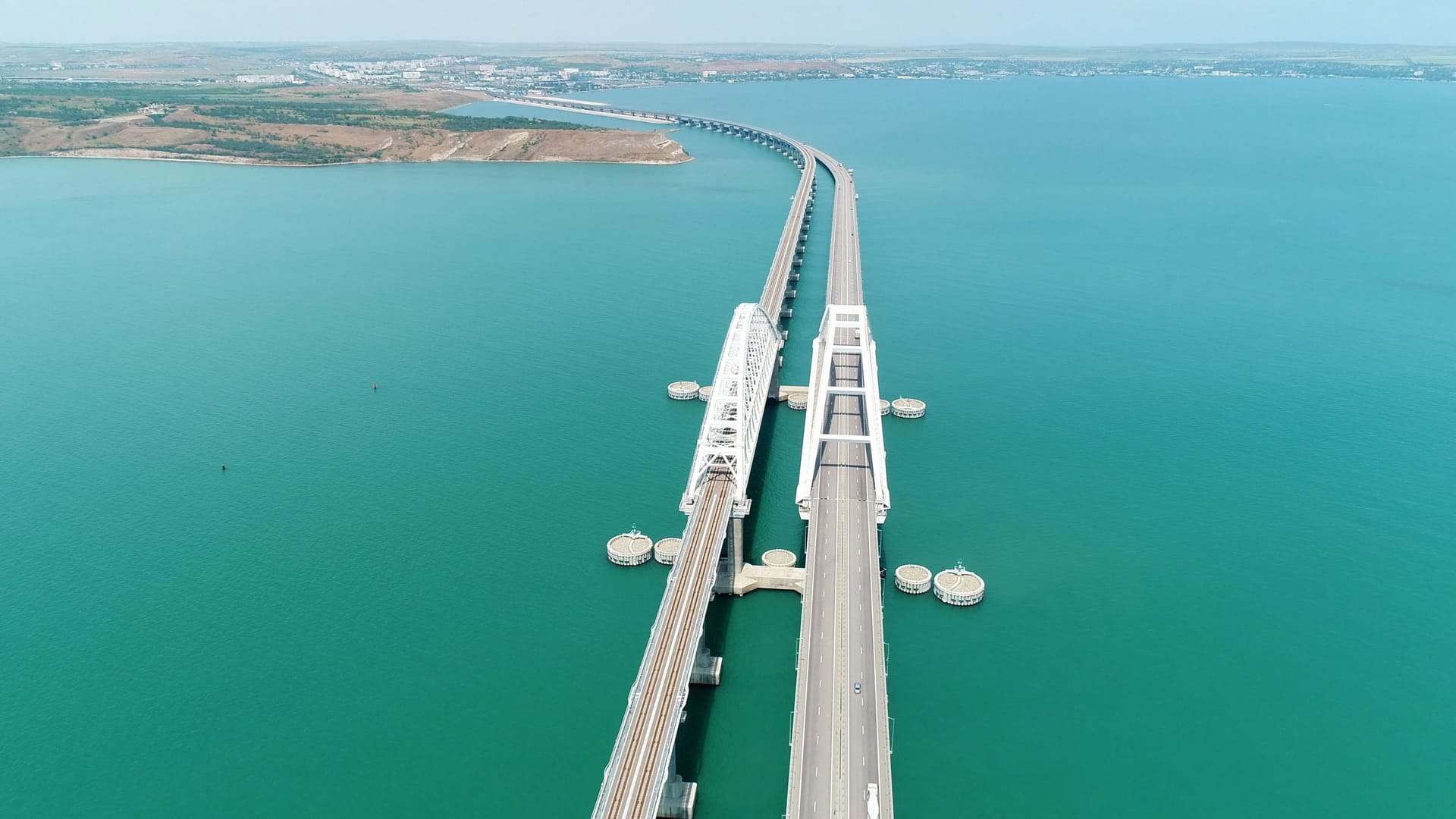 Aerial view of the crimean Bridge across the Kerch Strait. Shot. Amazing long bending bridge above calm turquoise sea.