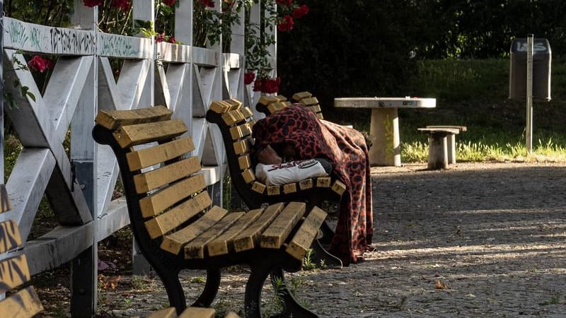 Ein Obdachloser liegt unter Decken auf einer Parkbank: Nicht nur im Winter haben Obdachlose wegen der Temperaturen, auch im Sommer können sie Probleme verursachen.