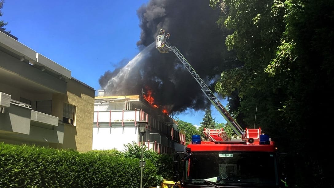 Einsatzkräfte der Feuerwehr löschen den Brand von einer Drehleiter aus: Baustoffe auf dem Dach eines Mehrfamilienhauses standen in Flammen. Einsatzkräfte der Feuerwehr löschen den Brand von einer Drehleiter aus: Baustoffe auf dem Dach eines Mehrfamilienhauses standen in Flammen.