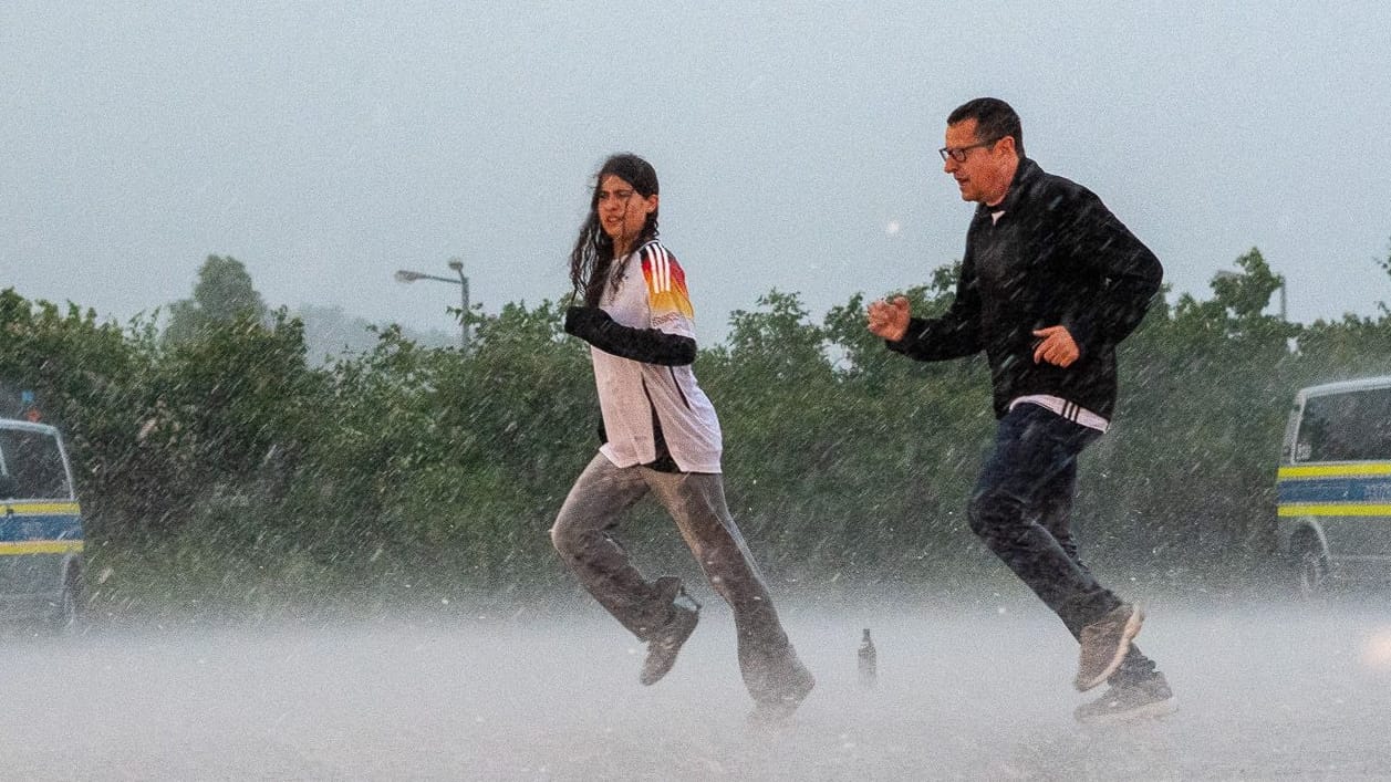 Fans flüchten vor der Allianz Arena vor dem Regen: Für den Abend wird im Münchner Raum ein Gewitter erwartet. Fans flüchten vor der Allianz Arena vor dem Regen: Für den Abend wird im Münchner Raum ein Gewitter erwartet.
