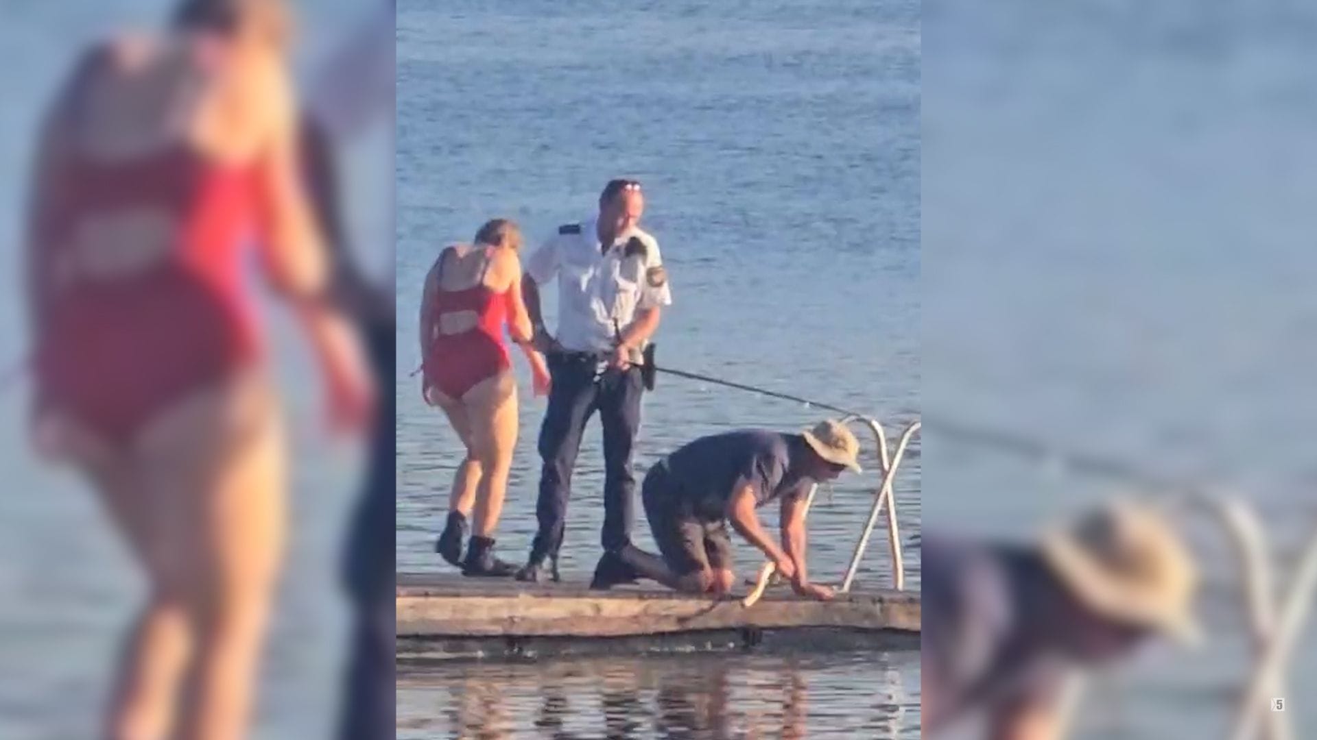Ein Augenzeugen-Bild zeigt: Ein Polizist ist vor Ort mit einem Angler im Einsatz, um den Fisch aus dem Wasser zu holen.