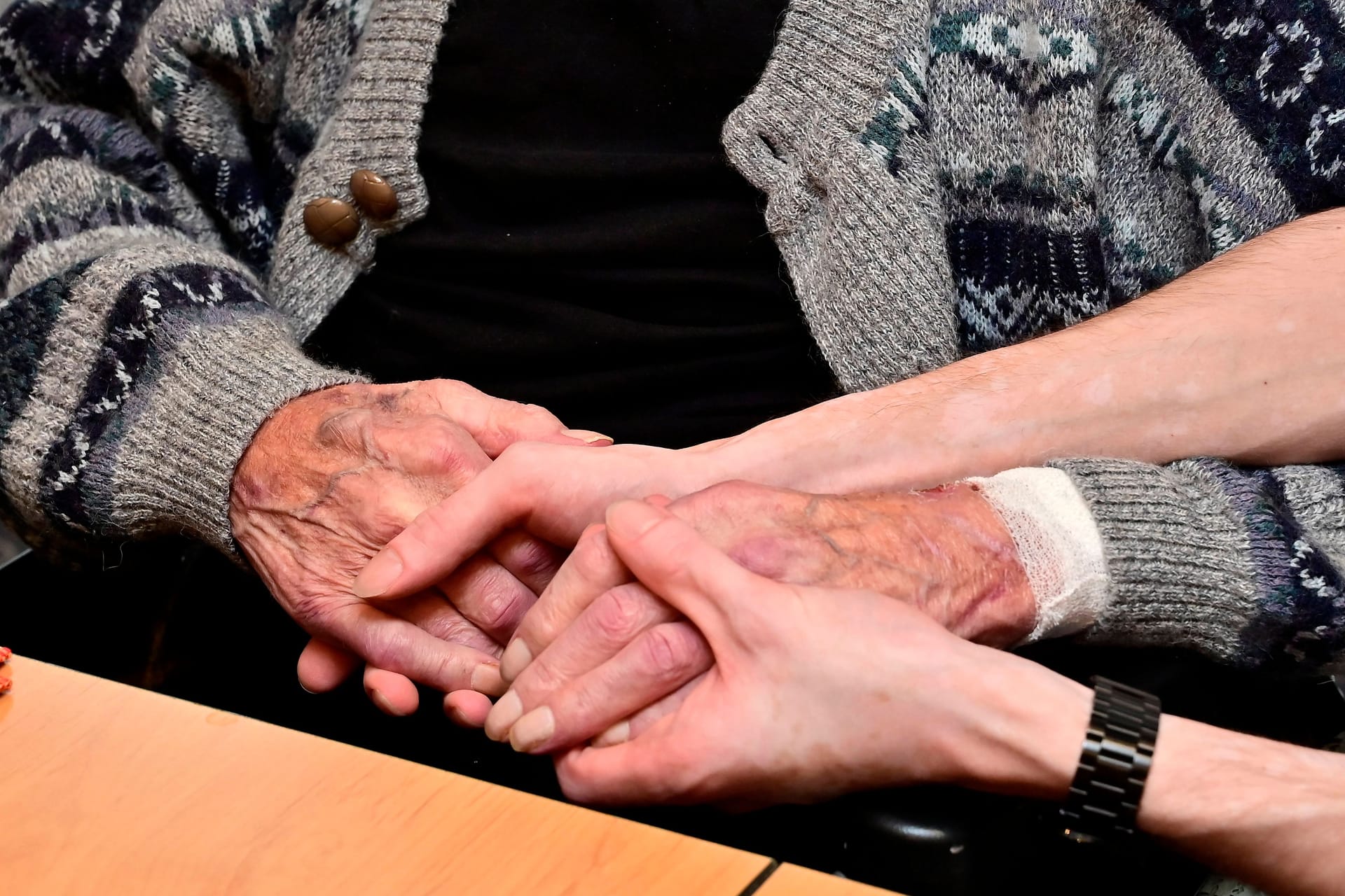 02.11.2023, Deutschland, Nordrhein-Westfalen, Ruhrgebiet, Essen. Christliches Hospiz in Essen-Werden. Ein Hospiz ist eine Einrichtung der Sterbebegleitung. Sehr oft wird mit Hospiz eine Pflegeeinrichtung bezeichnet, die nur ueber wenige Betten verfuegt und aehnlich wie ein Pfelegeheim organisiert ist. In Deutschland gibt es etwa 250 stationaere Hospize, 340 Palliativstationen in Krankenhaeusern sowie ueber 1500 ambulante Hospizdienste. Blick in den Gemeinschaftsraum. Pfleger beruehrt die Haende eines Gastes. Sterbebegleitung im Christlichen Hospiz Essen-Werden