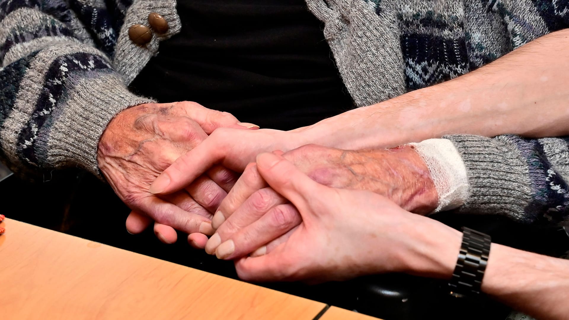 02.11.2023, Deutschland, Nordrhein-Westfalen, Ruhrgebiet, Essen. Christliches Hospiz in Essen-Werden. Ein Hospiz ist eine Einrichtung der Sterbebegleitung. Sehr oft wird mit Hospiz eine Pflegeeinrichtung bezeichnet, die nur ueber wenige Betten verfuegt und aehnlich wie ein Pfelegeheim organisiert ist. In Deutschland gibt es etwa 250 stationaere Hospize, 340 Palliativstationen in Krankenhaeusern sowie ueber 1500 ambulante Hospizdienste. Blick in den Gemeinschaftsraum. Pfleger beruehrt die Haende eines Gastes. Sterbebegleitung im Christlichen Hospiz Essen-Werden