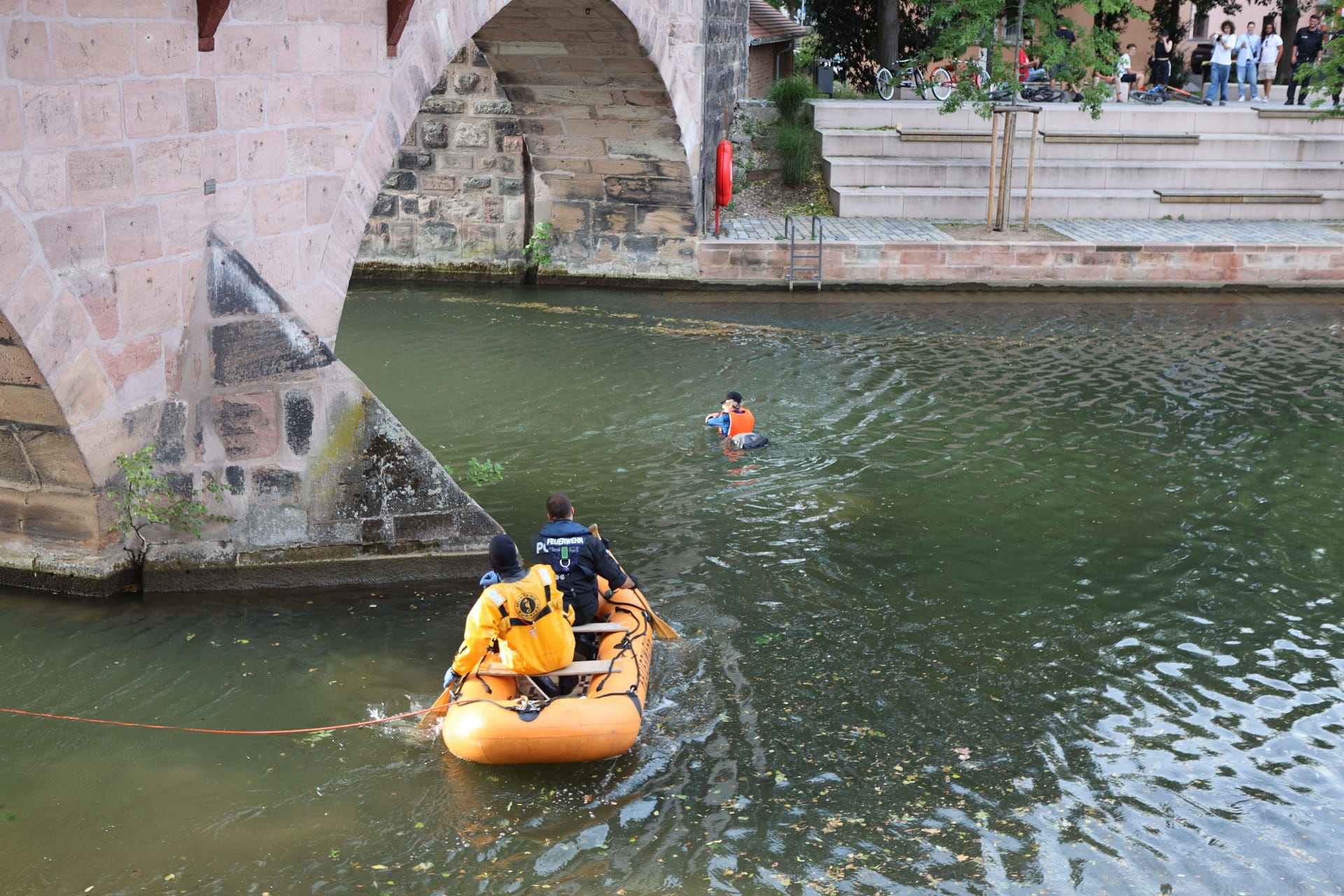 Ein Aktivist schwimmt in der Pegnitz: Die Aktivisten haben nach Polizeiangaben ihre Sicherung gelöst und sich ins Wasser fallen lassen – die Feuerwehr rettete sie mit einem Boot.