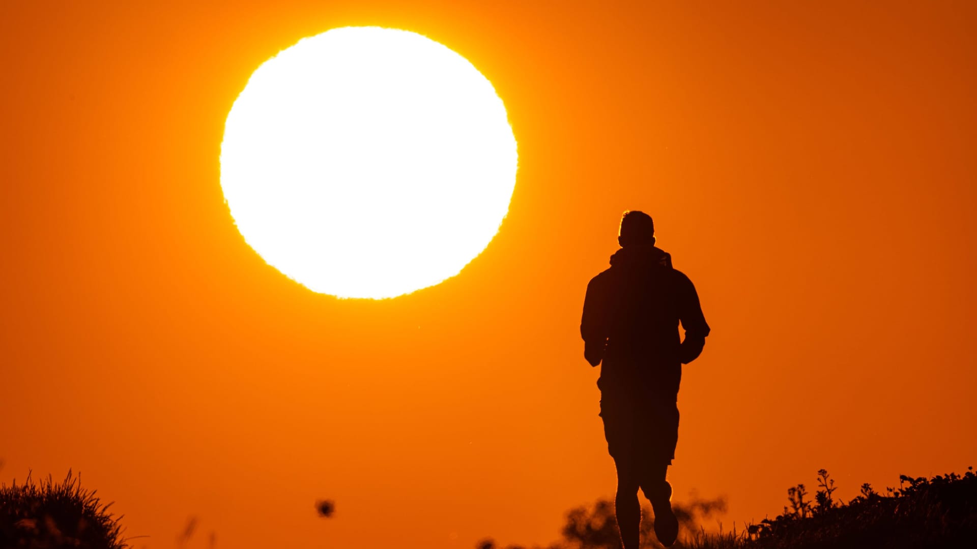 Ein Jogger läuft bei Sonnenaufgang auf einem Feldweg bei Frankfurt am Main (Symbolfoto): In den kommenden Tagen wird es in der Hessen-Metropole noch einmal richtig heiß.