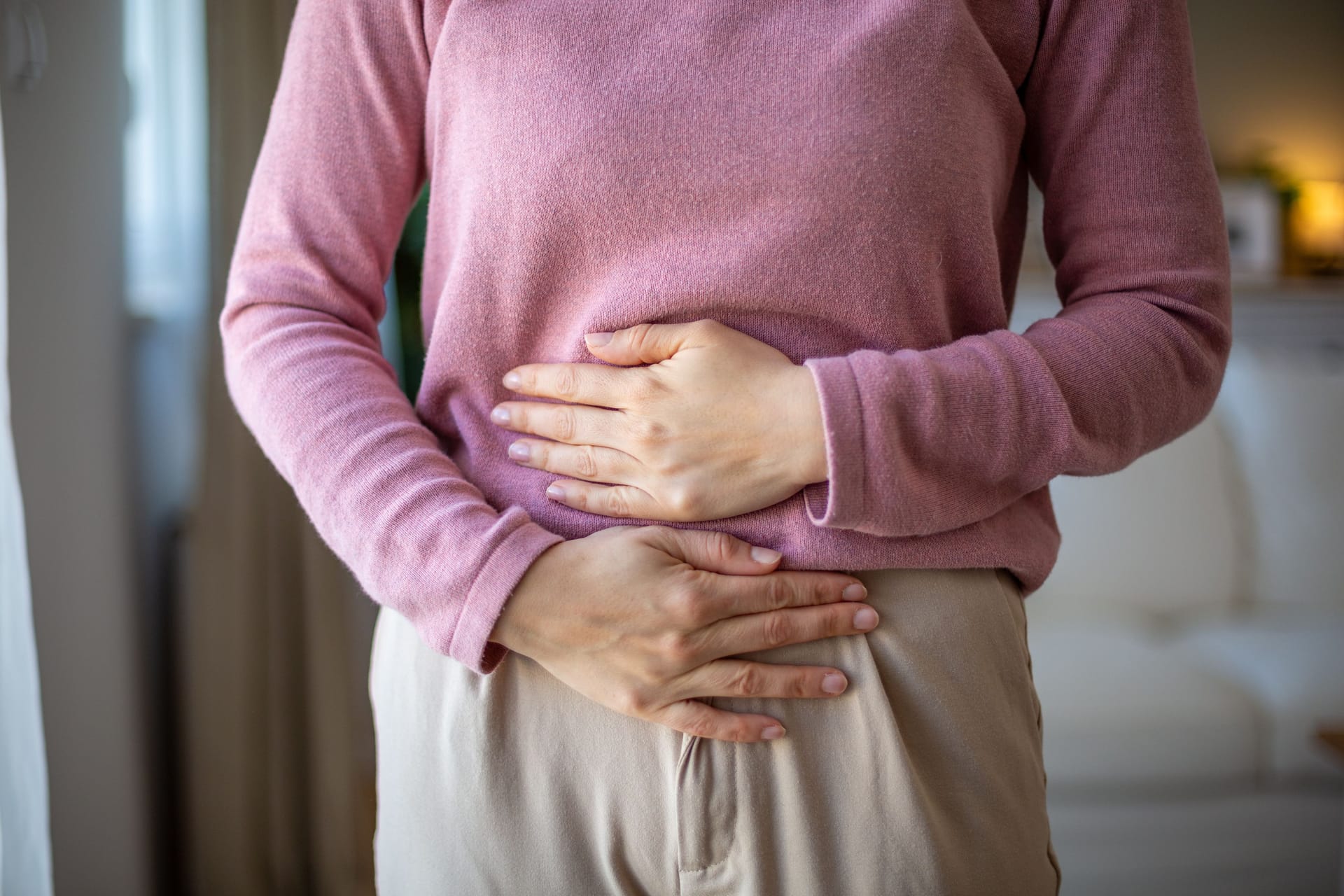 Frau hält sich den Bauch: Wer einen Blähbauch hat, kann meist zunächst mit Hausmitteln versuchen, die Symptome zu lindern.