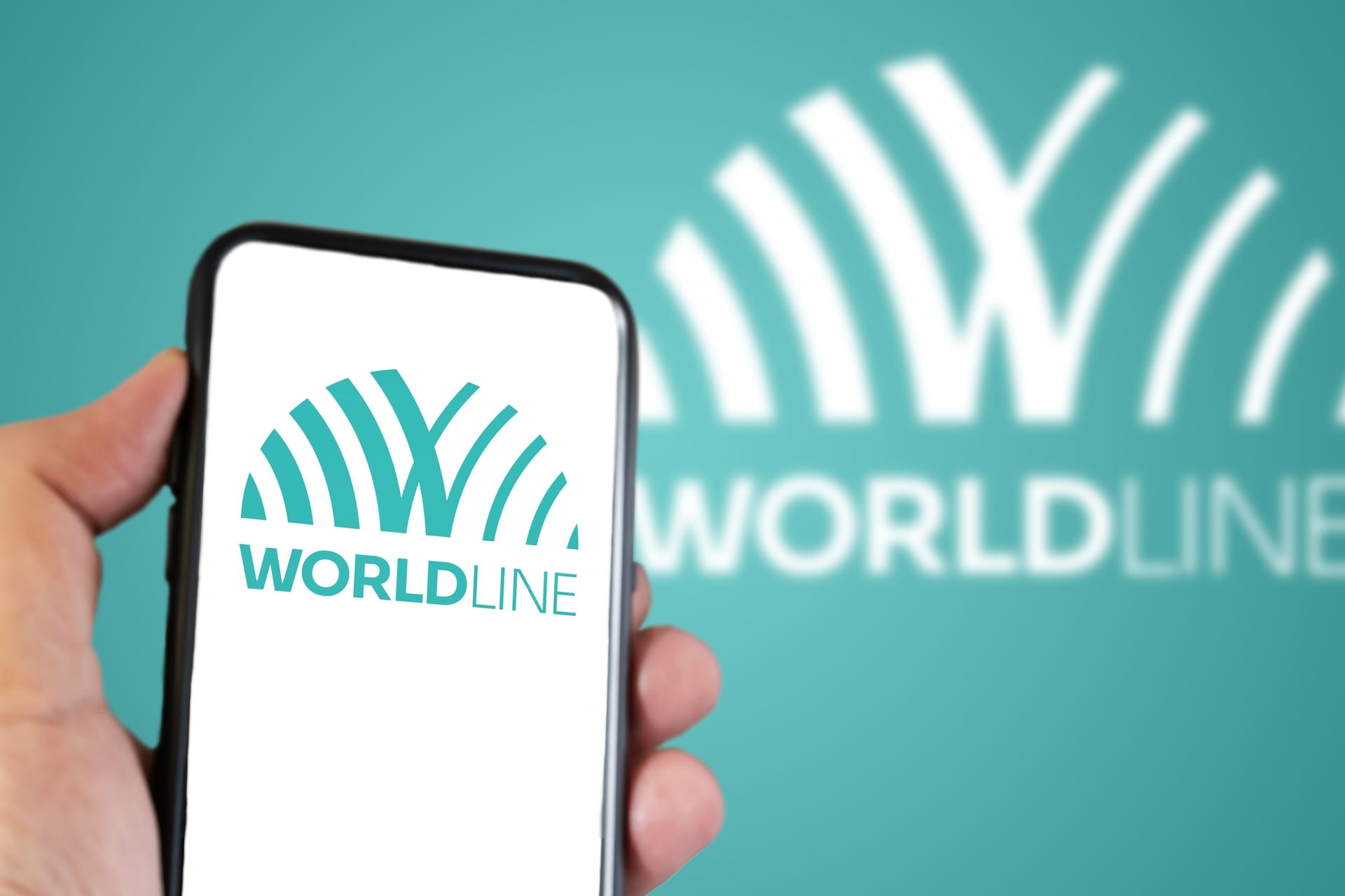 Hand holding a smartphone with the Worldline logo on the screen