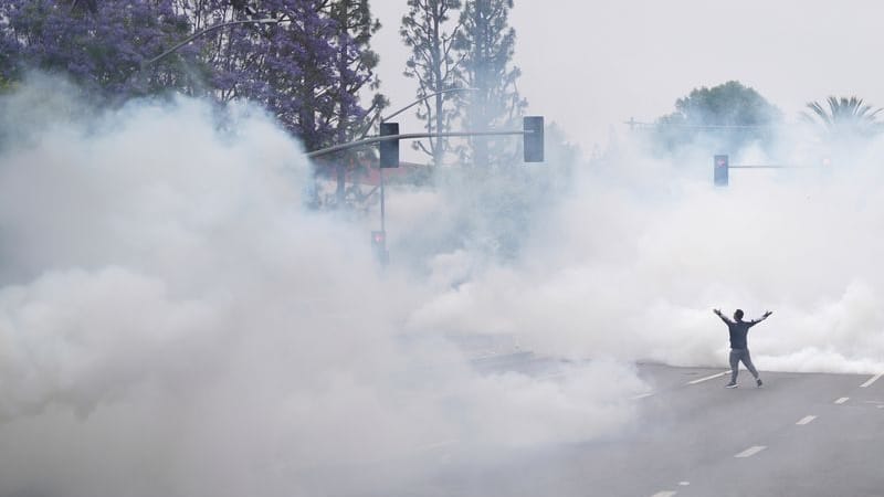 Rauch füllt die Straße, als ein Demonstrant den Grenzschutzbeamten gegenübersteht.