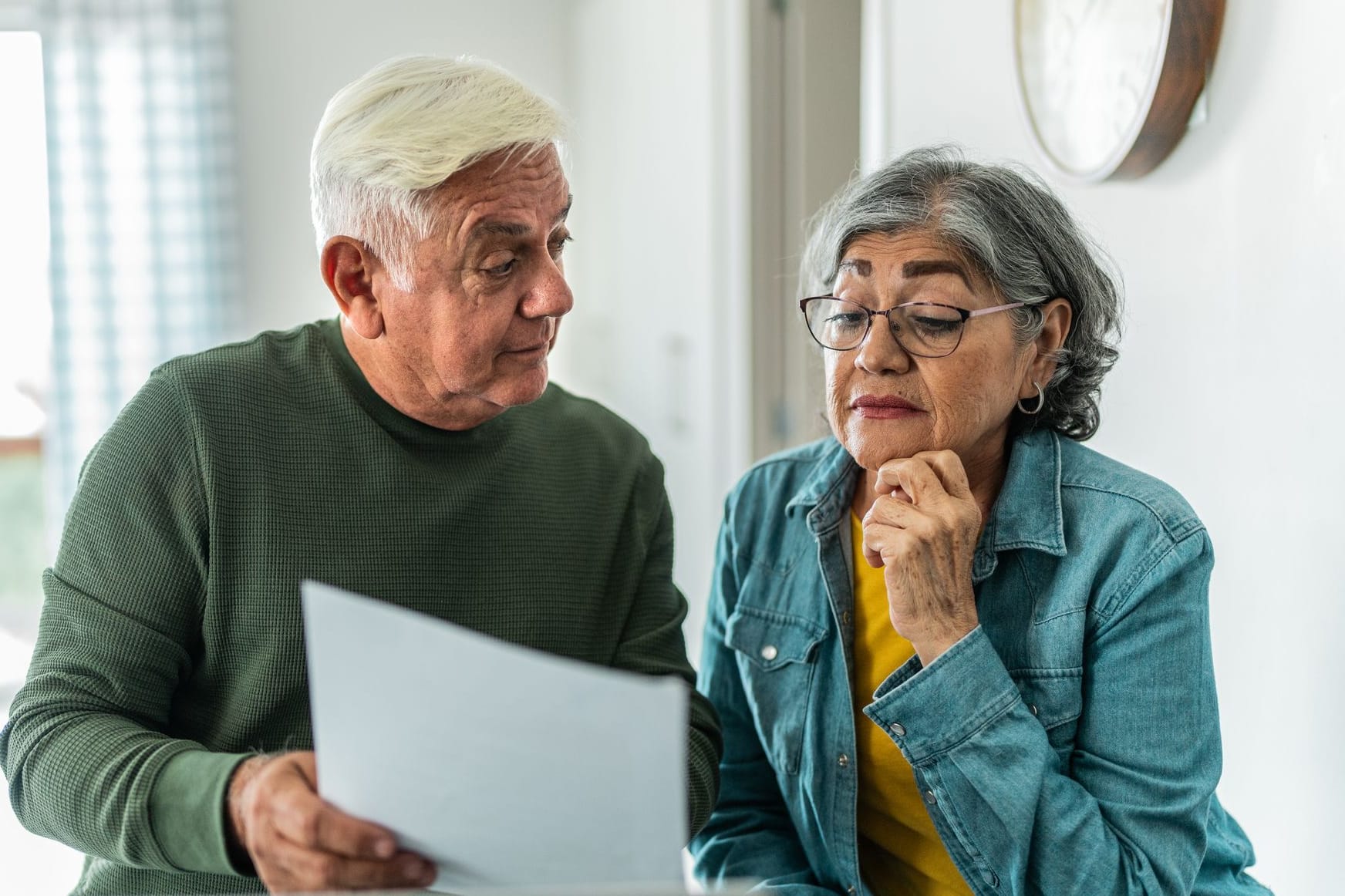 Rentnerpaar liest einen Bescheid: Der gestiegene Pflegebeitrag erreicht Rentner ab Juli 2025.