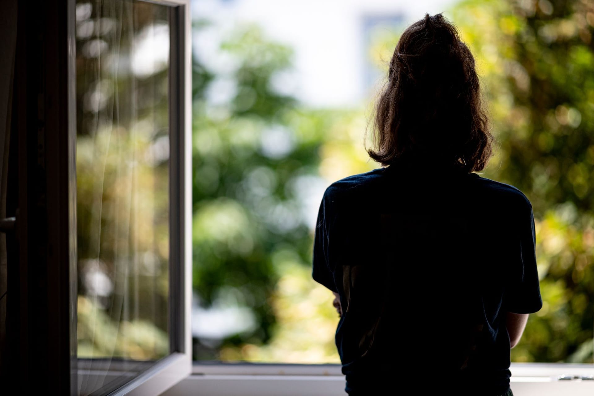 Eine Frau steht an einem offenen Fenster