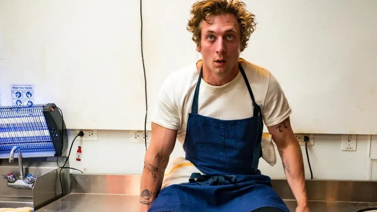 Szenenfoto aus der Serie "The Bear". Schauspieler Jeremy Allen White sitzt auf einem Tisch.