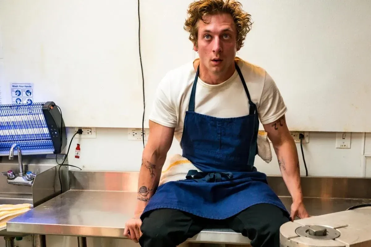 Szenenfoto aus der Serie "The Bear". Schauspieler Jeremy Allen White sitzt auf einem Tisch.