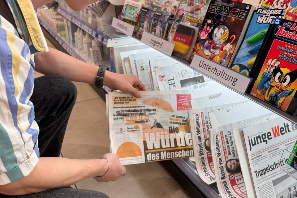 Ein Aktivist der "Neuen Generation" steckt eine gefälschte "Bild"-Zeitung in ein Regal: Die Polizei stellte keinen strafbaren Inhalt fest.