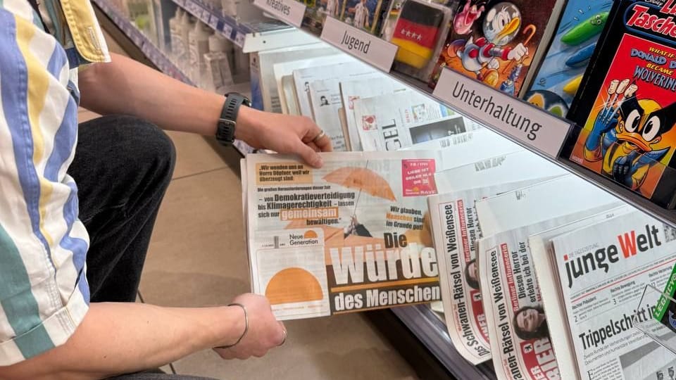 Ein Aktivist der "Neuen Generation" steckt eine gefälschte "Bild"-Zeitung in ein Regal: Die Polizei stellte keinen strafbaren Inhalt fest.