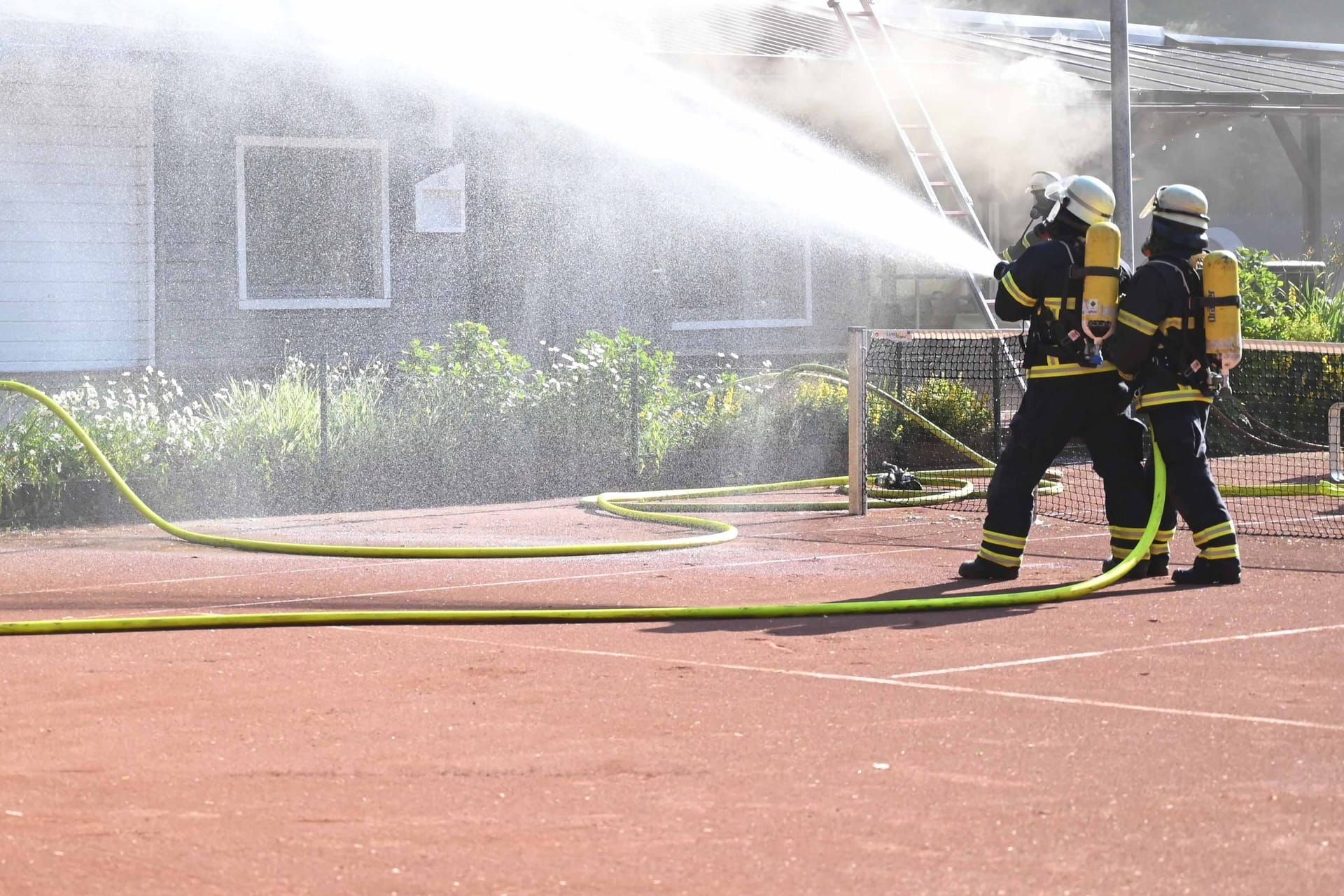 Feuerwehrleute löschen einen Brand an einem Tennisclub in Marmstorf: Der Einsatz zog sich bis in die Mittagsstunden hinein.