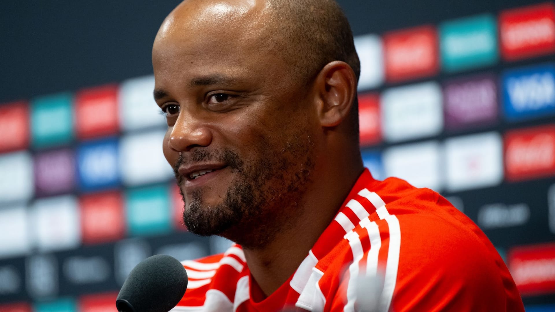 Trainer Vincent Kompany von München sitzt auf dem Podium und beantwortet die Fragen von den Journalisten.