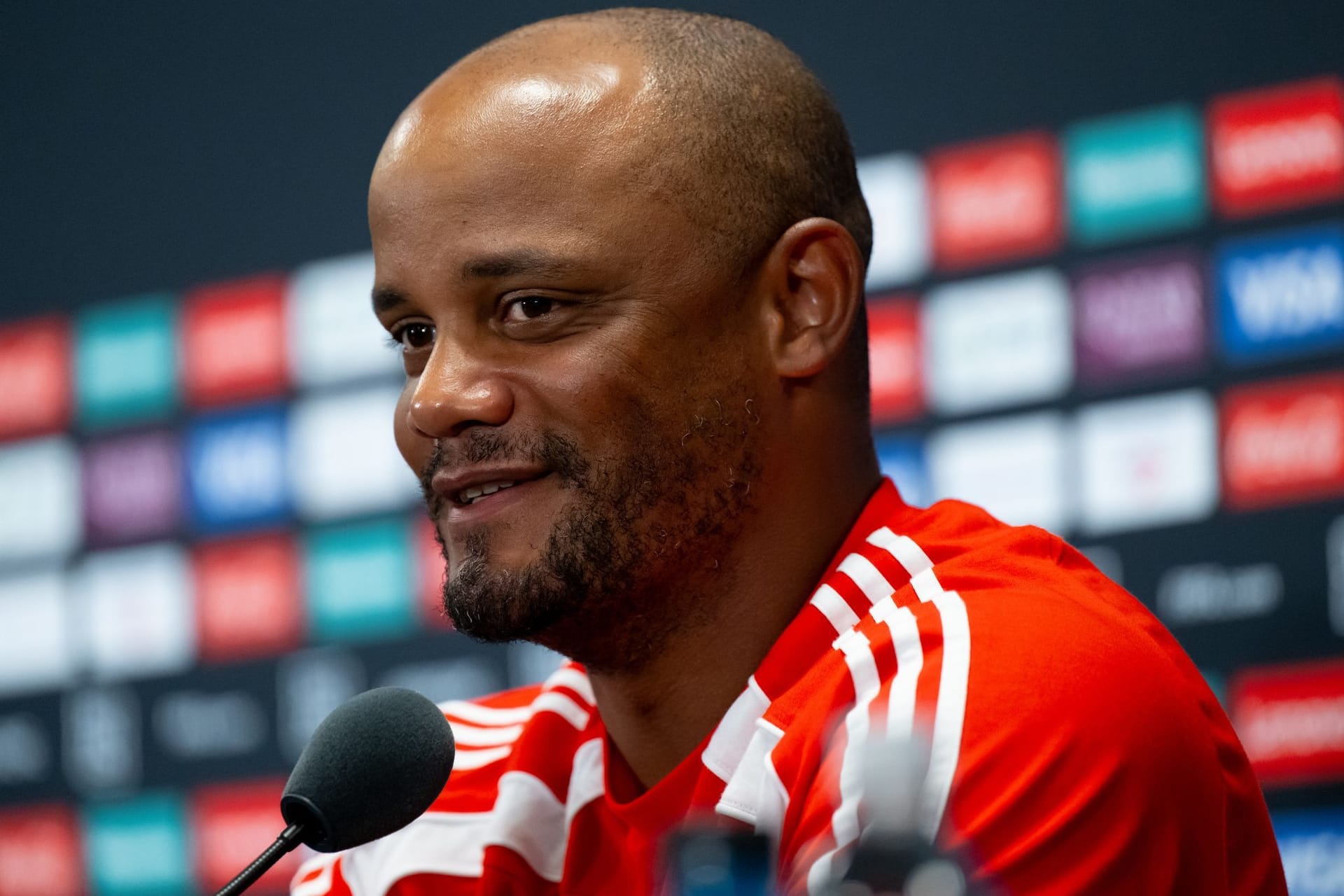 Trainer Vincent Kompany von München sitzt auf dem Podium und beantwortet die Fragen von den Journalisten.