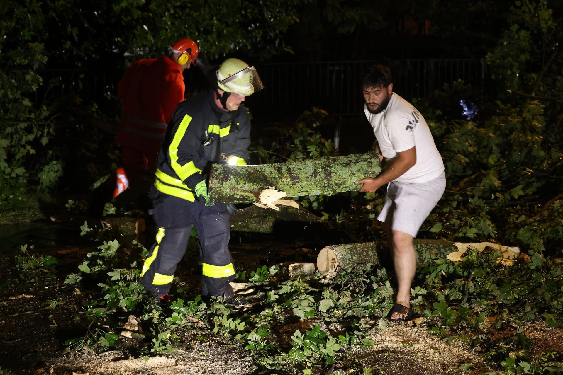 Feuerwehrleute und Anwohner räumen eine Straße mit umgestürzten Bäumen in Krefeld: Unwetter haben Zerstörung angerichtet.