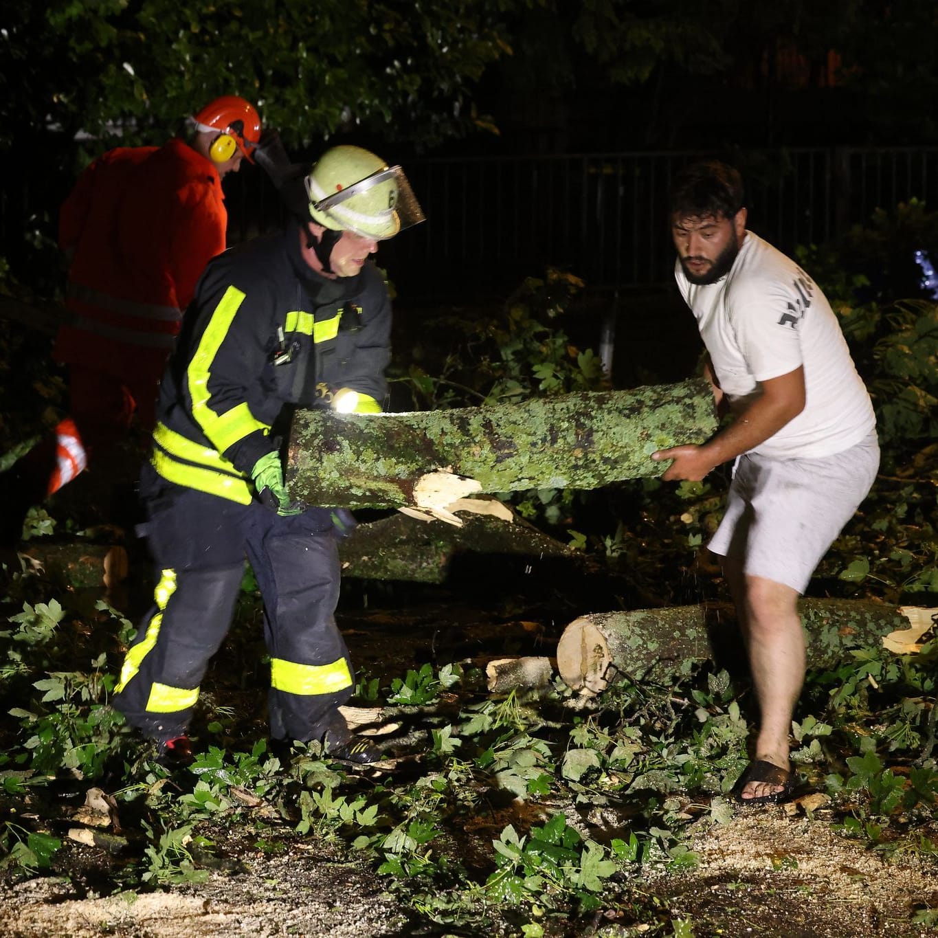 Feuerwehrleute und Anwohner räumen eine Straße mit umgestürzten Bäumen in Krefeld: Unwetter haben Zerstörung angerichtet.