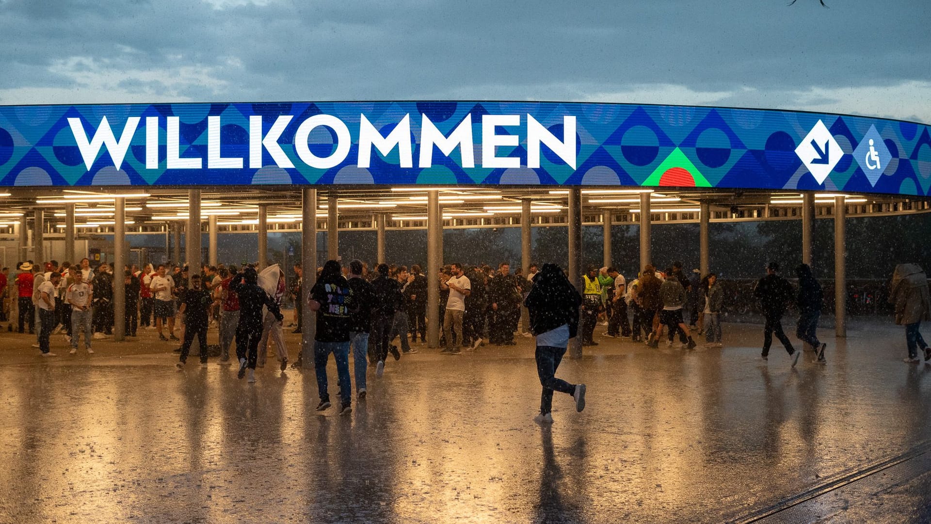 Der Regen setzt ein: Fans rennen in Richtung der Stadion-Eingänge.