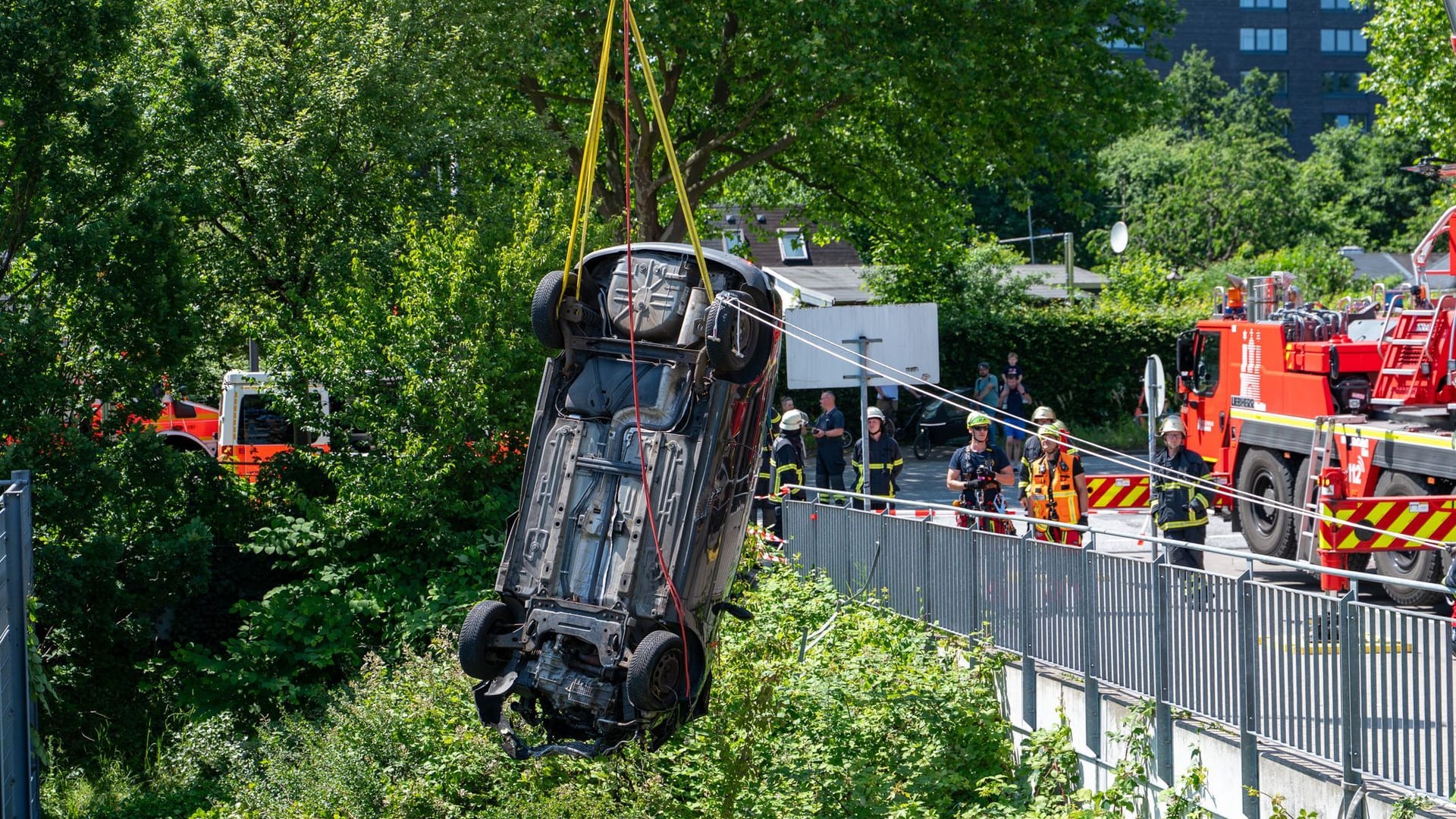 Einsatzkräfte der Feuerwehr bergen mit einem Kran das Unfallauto.
