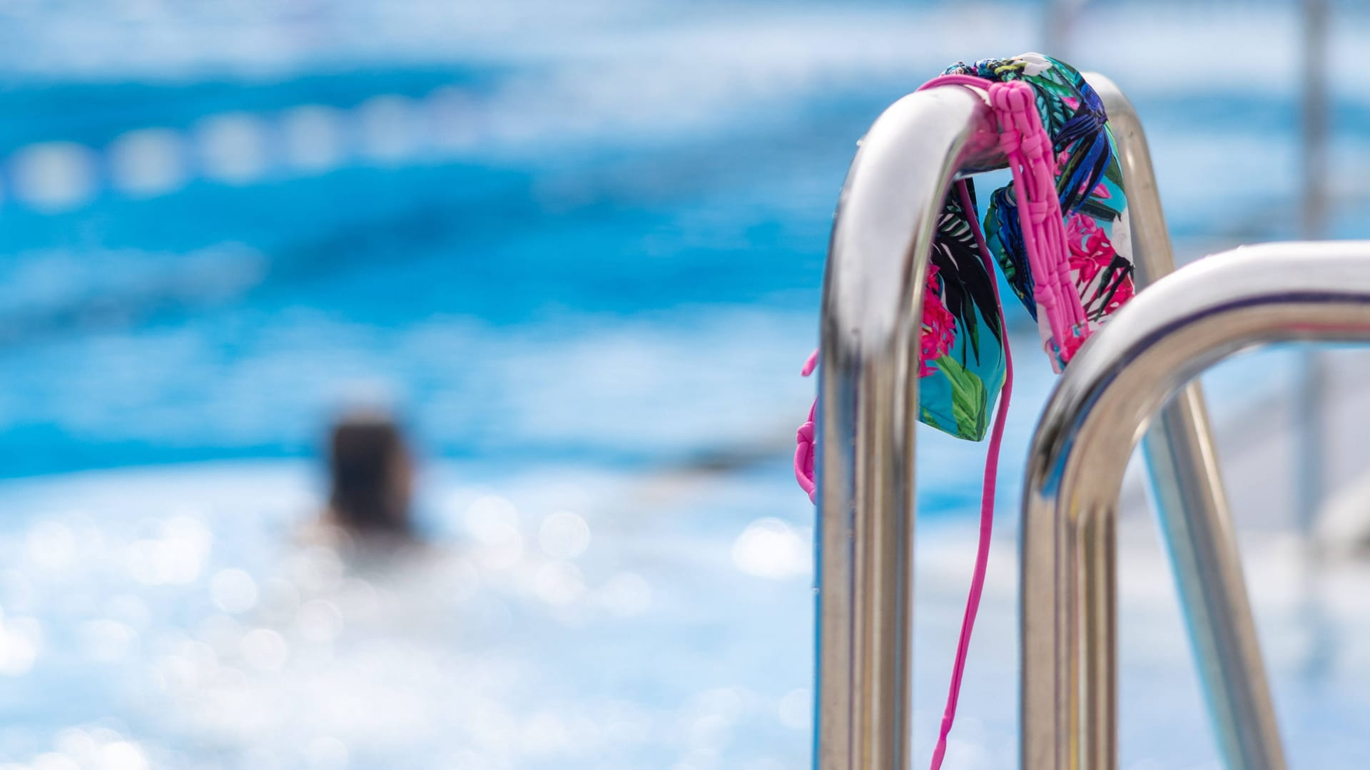 Ein buntes Bikini-Oberteil hängt an der Poolleiter (Symbolbild): In Uhingen hat ein privates Freibad eröffnet.