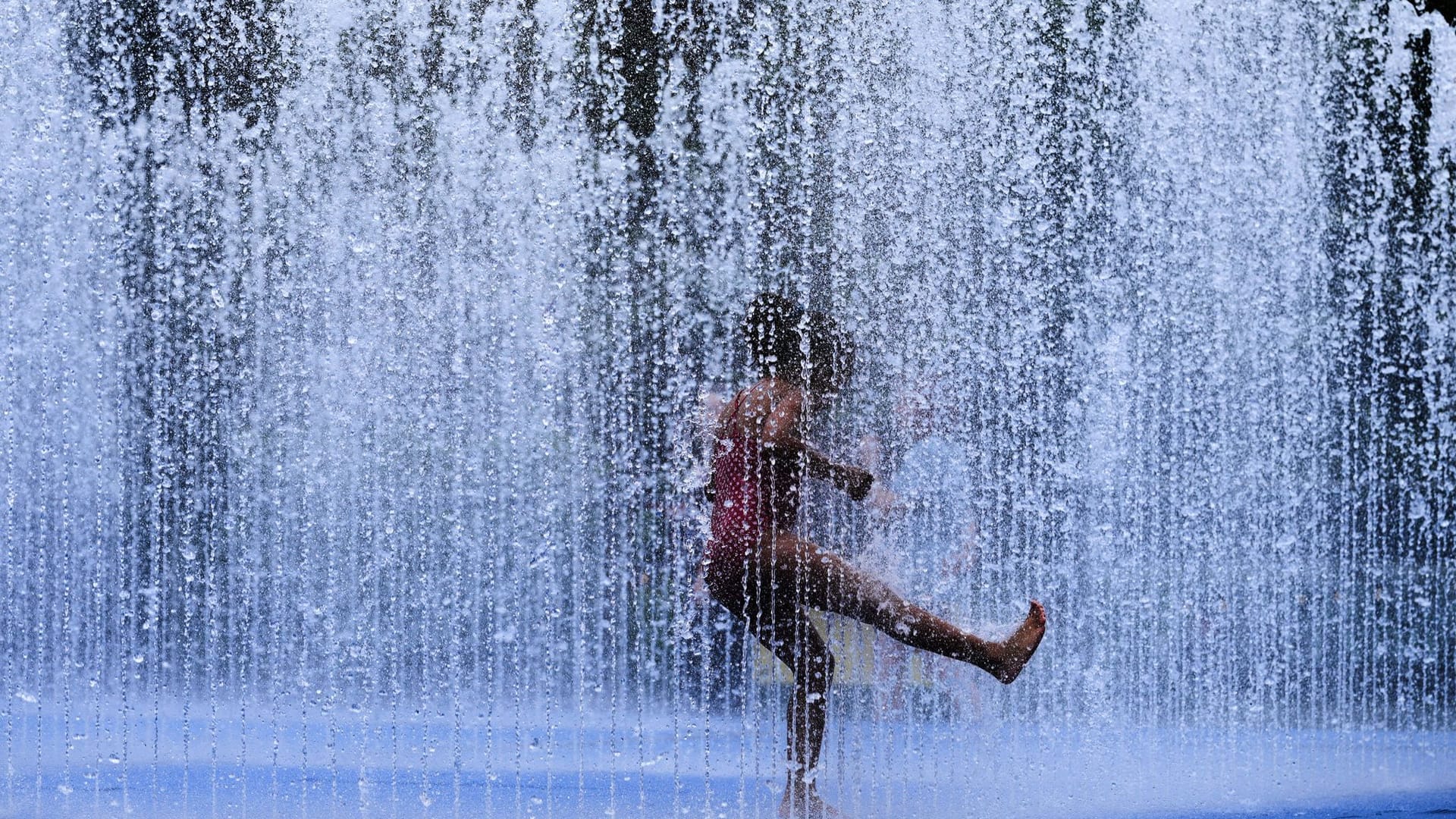 Ein Kind spielt in einem Springbrunnen (Symbolbild): Kühlende Orte dürften während der Hitzewelle gut besucht sein.